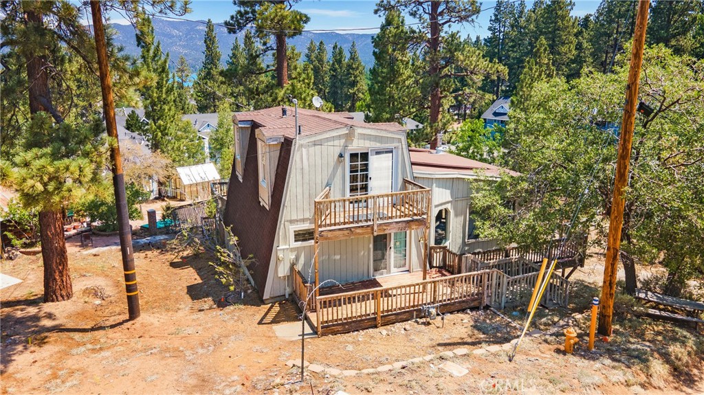 Surrounded by towering pines and fresh mountain air, this 2-bedroom, 2-bath home offers 1,433 sq ft of comfortable living space on a 5,850 sq ft lot in the heart of Big Bear. Expansive windows and multiple French doors bathe the interior in natural light, while vaulted ceilings add rustic charm. The spacious living area opens to a wraparound deck, perfect for outdoor entertaining, and one upstairs bedroom enjoys its own private balcony with serene treetop views. The bright kitchen features ample cabinetry and easy access to the dining space. Ideally located near Big Bear Lake, hiking and biking trails, ski resorts, and the shops and restaurants of The Village, this property offers the perfect blend of year-round living and vacation retreat potential.