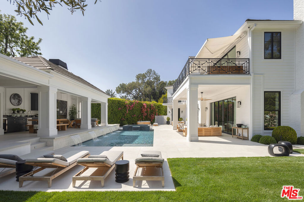 Positioned within the coveted Hidden Valley enclave of Beverly Hills, this impeccable estate offers privacy and tranquility behind secure gates, with 24/7 guard protection and lush, mature landscaping. Situated in one of the area's most prestigious guard-gated communities, this residence showcases timeless design, grand proportions, and a thoughtfully updated aesthetic that harmonizes with its natural surroundings. Every element of this home has been masterfully conceived to deliver an unparalleled living experience. A dramatic 24-foot ceiling in the entry foyer sets the tone, featuring custom-crafted millwork and elegant wrought-iron accents that echo throughout the interiors. Spanning approximately 12,000 square feet, the residence is graced with wide-plank white oak floors, 12-foot-high ceilings, and expansive windows that frame serene canyon vistas. The main level unfolds with a series of distinguished spaces, including a formal living room, office, formal dining room, and multiple powder rooms. A spacious family room seamlessly connects to the outdoor entertaining areas, where a sprawling backyard oasis includes a pool, spa, outdoor kitchen, bar, dining pavilion, and fire pit lounge. The chef's kitchen is a masterpiece of both design and functionality, outfitted with honed Calacatta marble countertops, a La Cornue 1908 range and oven, Wolf microwave, Sub-Zero refrigerator and freezer, dual Miele dishwashers, a wine fridge, and an oversized eat-in island, all framed by crisp white cabinetry. Two ensuite bedrooms and a two-car garage complete the main floor. Effortless access to the estate's three levels is provided by a private elevator. Upstairs, the opulent primary suite offers a serene retreat with a fireplace, a balcony with picturesque views, dual marble bathrooms featuring soaking tubs, and a pair of custom dressing rooms with abundant built-in storage. Four additional ensuite bedrooms, each with spacious dressing closets, complete this floor. The lower level features a host of amenities for relaxation and entertainment. With 11-foot ceilings, this space includes a cozy home theater, a wet bar, lounge, gaming area, temperature-controlled wine room, fully equipped fitness studio, and laundry facilities. Additionally, the subterranean auto gallery spanning approximately 2,000 square feet boasts a revolving car turntable and accommodates up to six vehicles, offering limitless opportunities for customization. Fully automated through Savant and Lutron systems, the home's technology provides seamless control over lighting, drapery, audio, televisions, fireplaces, and entry systems, ensuring modern convenience at every turn. Perfectly positioned within top-tier school districts and offering convenient access to Beverly Hills, the Westside, and the Valley's finest shopping, dining, and nightlife, this estate is a rare offering that combines sophistication, comfort, and cutting-edge amenities.