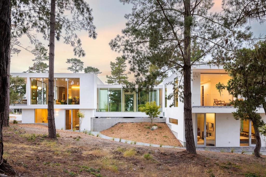 With sweeping views of Spyglass Hills 11th fairway and filtered ocean vistas, the Waterbridge House is an extraordinary Scandinavian-Japanese minimalist estate. This newly constructed compound is comprised of the stunning main house, a private ADU, and a Tea House (Guest House) floating on water. The striking architecture embraces intentional simplicity, blending natural elements with modern form. Two architectural axes, interior and exterior, guide you through spaces that reveal and conceal, including the "Waterbridge," a glazed walkway over a tranquil pond. The sculptural Cloud Steps lead to a light-filled interior where polished concrete floors, Western floor-to-ceiling windows, Italian concealed Infinity doors, and Poliform cabinetry define quiet luxury. Sustainability meets sophistication with triple-glazed windows, radiant heat, and an automated energy recovery system. From Sub-Zero, Wolf, and Miele appliances to Italian Flos lighting and Simply White plaster walls, every detail reflects enduring craftsmanship and environmental mindfulness. Located in the heart of Pebble Beach near The Lodge and by the Spyglass Club House, Waterbridge House is a half mile to the beach and a short drive from all the wonderful amenities of Carmel, Big Sur, and the Monterey Peninsula.