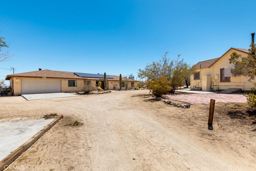 2 Single Family Residence dwellings and 2.35 acres of Panoramic Indian Cove Canyon. The main house was built in 1990 by one of the original homesteader's of the area, and has been immaculately taken care of by the family. Step into 2,917 square feet of "South Western Ranch Style" living, with a beautiful full size swimming pool.  4 spacious bedrooms with 2 Primary Suites on opposite ends of the home with their own private entrances. 3 full baths including shower, shower tub combo, and deep jet tub with ample closets and storage throughout the home. Dual Evaporative Coolers to keep this home cool in summer and New Central Heat with a Gas/Wood Burning Fire Place for those cold ambient nights. Also included New: roof, garage door opener, pool pump, and 2 gas water heaters. Finished 2 car attached garage with workshop and large mudroom for full size gas or electric laundry.  Host dinner parties with a dreamy Chef's Kitchen, and dinning room that opens up to the front veranda. The second Guest House, not attached, has its own private driveway, perfect for art studio or guests. The original structure was build in 1935 and includes its own septic tank. 1 bedroom, 1 bath, with beautiful wood paneling in a large kitchen, living room and breakfast bar. Minutes drive away on the same road to Indian Cove Campground where you can camp and hike into the Joshua Tree State Park with some of the most unique rock formations in the Hi Desert. Plus if you are interested in developing or purchasing the surrounding lots so others won't, please inquire. 2 additional lots For Sale to the South, one of which on the Hwy is zoned for Commercial. Buffer lot to commercial included in Sale with full price offer. This special residence wont last long. Bring All offers!