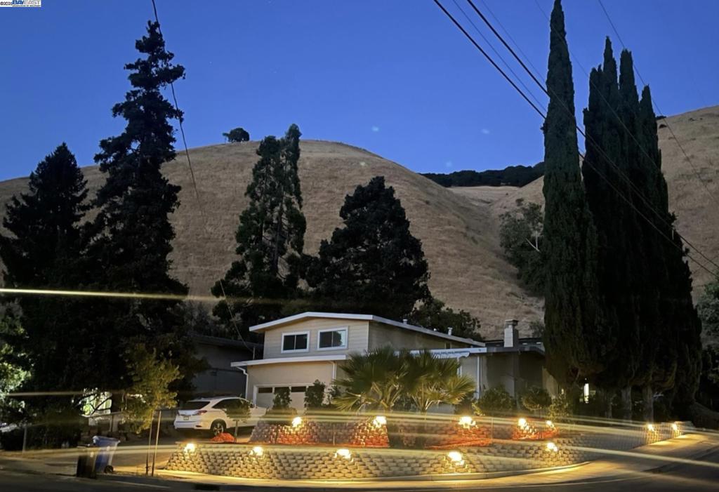 Tucked away in the highly desirable Canyon Heights community, this charming corner-lot residence offers a rare blend of functionality, privacy, and versatility. Officially listed as a 3-bedroom, 2-bathroom home, this thoughtfully upgraded property also features a lower-level bonus suite complete with a closet, private entrance, and a full bath—ideal for use as a fourth bedroom, guest quarters, or income-generating rental. Step outside and discover your own outdoor oasis: recently landscaped front, side, and backyard spaces illuminated by custom lighting that creates a tranquil ambiance perfect for evening gatherings or quiet relaxation. The expansive patio, lush lawn, and string-lit entertaining area make this home an entertainer's dream. Inside, enjoy the comfort of central heat and air conditioning, dual-pane windows, and a tankless water heater. The kitchen boasts a spacious island, and stainless steel appliances including a gas cooktop. Enjoy scenic hillside views and a peaceful neighborhood feel—all just minutes from schools, BART, Highway 84/680, and the historic Niles District with shops, dining, and parks. Whether you're looking for multi-generational living, rental potential, or simply a unique home with room to grow—this Fremont gem delivers.