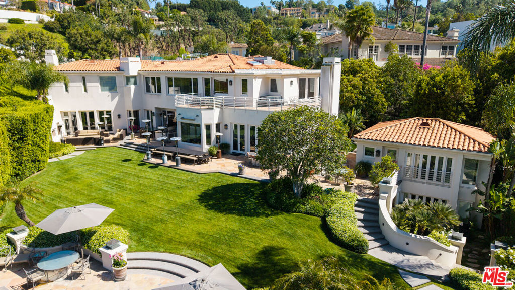 One of the few premier view properties in Mulholland Estates, this private tennis court art deco estate sits on 1.3 acres with spectacular city lights views and views of beautiful verdant hills . Located in one of the most coveted guard-gated communities, the home offers exceptional ceiling heights and perfect scale and elegance. This elegant art deco deco designer home offers grand formal living areas, a gourmet kitchen with separate prep space, and floor-to-ceiling glass doors open to an infinity pool, full-size tennis court, and expansive indoor outdoor entertaining areas. Additional highlights include a separate staff wing, gym, elevator, 10-car garage, and an entertainment level with a professional theater, game room, wine room, satellite kitchen, and offices. A detached two-story guesthouse completes this rare and refined offering.