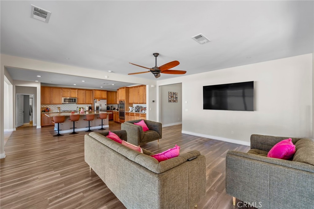 This expansive two-story home offers approximately 3,753 square feet of thoughtfully designed living space, including 6 bedrooms and 4 full bathrooms, making it ideal for growing families or multi-generational living. The layout features a spacious living area, a formal dining room, and a gourmet kitchen complete with an oversized granite island, double ovens, walk-in pantry, and ample cabinetry. Throughout the home, you'll find elegant finishes like dark wood-style laminate flooring downstairs, plush carpeting upstairs, and granite countertops in kitchens and baths. In addition to having a gorgeous interior layout, by stepping outside you'll find a beautifully maintained backyard with a wraparound concrete patio, ideal for relaxing, hosting, or gardening.