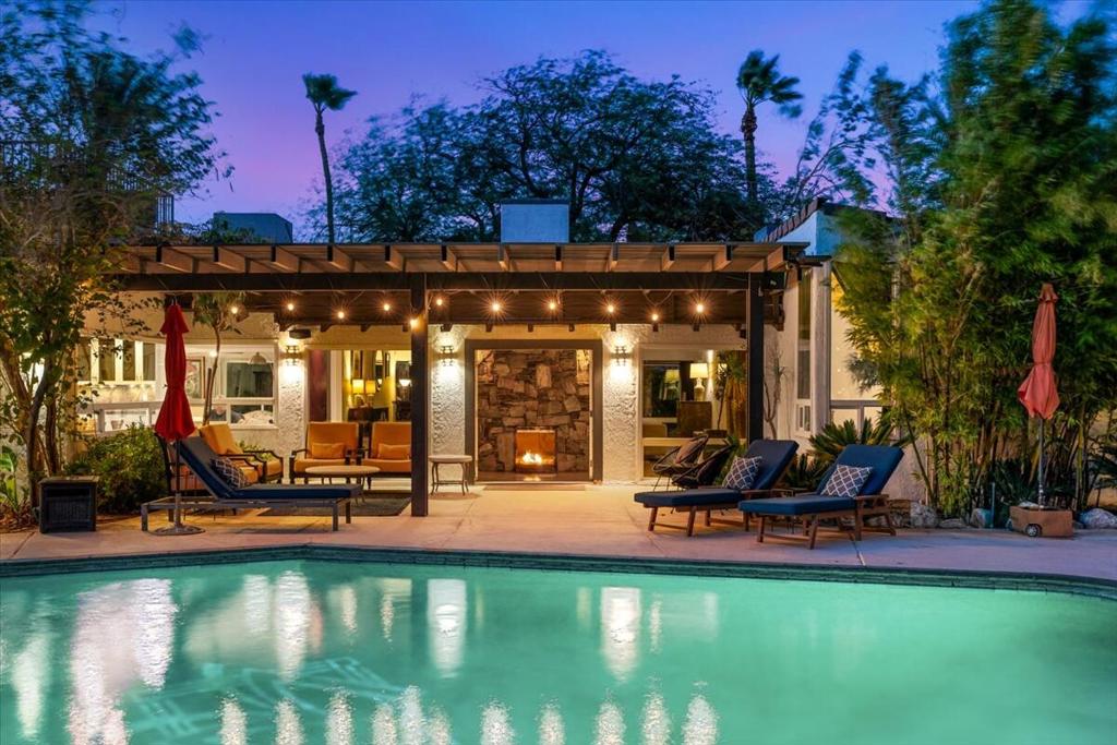 Experience timeless Palm Springs elegance in this private 1936 mini-estate, set on over half an acre of fee simple land with sweeping western mountain views. Surrounded by lush, botanical garden-style grounds adorned with mature fruit trees, the property embodies both serenity and sophistication.The main residence offers three bedrooms (two ensuite) and three baths, with a vaulted great room anchored by a dramatic floor-to-ceiling native stone fireplace--a striking centerpiece reminiscent of the desert ranch homes from Hollywood's golden era. An attached casita provides a private retreat with its own private entrance, kitchen, bath, and dedicated parking.While already inviting, the property presents a unique opportunity for thoughtful renovation. With updates, its historic character and resort-style setting can be elevated even further, blending Palm Springs ranch charm with modern luxury. Outdoors, a saltwater pool, shaded dining area, large grassy area and vibrant mature landscaping create a secluded haven for relaxation and entertaining on a grand scale. An owned solar system with 24 panels ensures modern efficiency without compromise.An oasis of calm that's only minutes from downtown Palm Springs, this turnkey furnished estate offers effortless access to fine dining, boutique shopping, hiking, and cultural attractions. A rare opportunity to own a retreat where history, beauty, and future potential converge. The possibilities are endless.