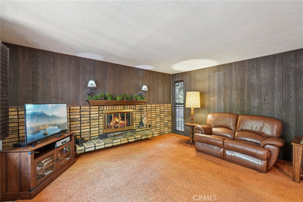 With level entry and a detached two-car garage that includes a storage room beneath it, this versatile property offers a rare combination of usable space, flexible potential, and a scenic setting. A breezeway leads to the main residence, a single-level 2 bedroom, 2.5 bathroom home featuring a formal living room with a raised hearth fireplace and a spacious great room with vaulted ceilings and walls of windows that bring in natural light and open to an expansive deck. The great room flows seamlessly into the open kitchen, which offers extensive counter space, abundant cabinetry, and a laundry area just off to the side. The primary suite includes its own private deck with forest views, a walk-in closet, and an en-suite 3/4 bath, while the second bedroom is adjacent to a full hall bath. Below the main level lies approximately 1,600 square feet of partially framed but unfinished space with a layout that could support a future extension of the main home or a separate lock-off unit with its own attached garage. Situated on a street-to-street lot with a flat backyard, mature conifers, and a sprawling walnut tree, the property offers privacy, space, and opportunity—all just steps from the national forest.