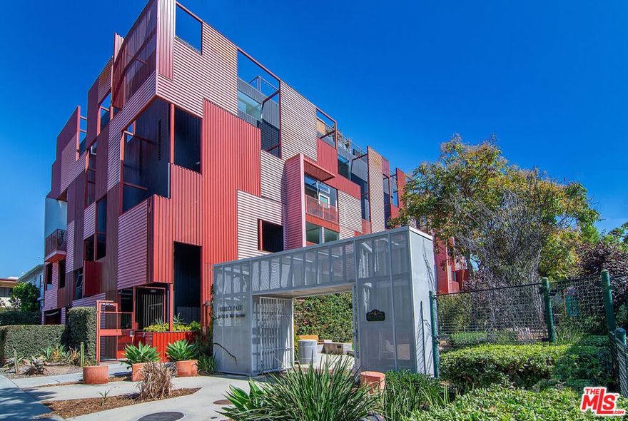 Architectural 2-bedroom, 3-bathroom top-floor townhouse designed by renowned architect Lorcan O'Herlihy. Expansive floor-to-ceiling windows, soaring ceilings, and an open-concept layout flood the home with natural light and frame sweeping views of the Hollywood Hills and Formosa Park. The spacious living and dining area, including a dry bar and wine fridge, flows effortlessly into a sleek modern kitchen featuring stone countertops, bar seating, stainless steel appliances, recessed lighting, and abundant cabinetry. Off the kitchen, a versatile office/flex space with built-in shelving is complemented by a powder bath. Upstairs, the primary suite offers a walk-in closet with custom cabinetry, Hollywood Hills views, and an ensuite bathroom with a walk-in shower. A second loft-style bedroom features a custom built-in closet, its own ensuite bath with a shower/tub combo, and access to the private Trex rooftop deck where panoramic city and mountain views capture the essence of L.A. living, from the Hollywood Sign to Griffith Observatory. Additional highlights include central AC/heat, automatic window shades, two assigned parking spaces with an EV charger, three guest parking spaces, and 24-hour access to Formosa Park. This architectural gem embodies the vibrant lifestyle that defines West Hollywood, just moments from the city's best shopping, dining, and entertainment.