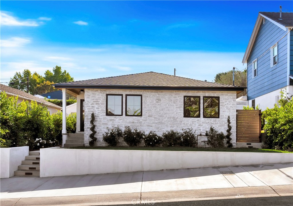 Welcome to this charming 3 bedroom, 2 bathroom home located in the highly desirable Tree Section of Manhattan Beach. From the moment you arrive, you're welcomed by blooming rose bushes and a classic white brick-accented exterior that exudes warmth and storybook curb appeal. Step inside and you’ll be greeted by an abundance of natural light and a warm, modern-organic aesthetic. The living room features a beautifully lime washed fireplace, adding texture and character to the space. The heart of the home is the stunning kitchen, complete with custom white oak cabinetry, paneled appliances, and elegant porcelain marble countertops. A wide pass-through window opens to the back porch, creating a seamless indoor-outdoor dining experience that’s perfect for enjoying ocean breezes and entertaining guests. The open floor plan offers both functionality and comfort, with thoughtful details throughout. Down the hallway, you'll find two bedrooms and a guest bathroom featuring porcelain brick tiles and soft cream marble floors. The serene primary suite overlooks the peaceful porch and includes custom closet cabinetry and a beautifully finished en-suite bathroom with a dual sink vanity, white marble shower walls, and a blend of cream and white marble flooring. With side street access, the garage offers convenience and privacy, and adjacent to it is an additional outdoor space, perfect for relaxing in the Manhattan Beach sun. Just minutes from the beach, local parks, top-rated schools, and a vibrant dining and shopping scene, this home is nestled in one of Manhattan Beach’s most quaint, community oriented neighborhoods that exudes laid-back yet sophisticated Southern California lifestyle!