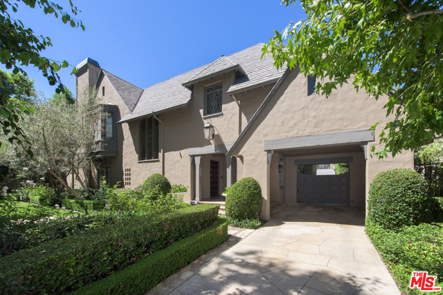Fabulous French Country Estate with lush landscaping on the best street in Hancock Park! Step through verdant gardens via a covered entry with Porte Cochere into a welcoming two-story grand entrance hall with wrap around stairway. High ceilings and generous volumes define a view to the great living room and adjoining family room both with fireplace and windows looking on to green scapes. Enter the elegant formal dining room with large french doors and views of the private backyard with sculpted topiary, and a sparkling saltwater pool cited in a gorgeous garden surrounded by Magnolia trees, gardenias, and tall hedges. Outside, a pergola shades a romantic exterior dining area with outdoor fireplace. Upstairs are four bedrooms, a lovely master with a luxurious bath and an extra large closet. Also featured are two bedrooms downstairs, and a one bedroom detached guest house. Wonderful family home and a very rare offering.