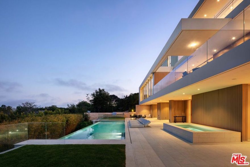 An evolution of Modernist Architecture designed with both purpose and intention to create a sublime experience of space and light. This Woods+Dangaren 8 bed 11 bath home + detached guest house is perched high above the Pacific Ocean in the highly coveted Upper Riviera. Majestic 180 coastline + city views are revealed through sliding walls of glass and framed openings to seamlessly connect indoor and outdoor spaces. The main floor introduces warm, organic materials to the experience with Duchateau flooring, custom casework, rift-oak paneling, and rough-hewn limestone to the living and dining areas. An open chefs kitchen with expansive views is complete with Miele appliances, Calacatta stone island, secondary kitchen, and open concept great room. Upstairs, beams of daylight diffuse through the transparent 3 story staircase as kinetic art. Skylights and glass envelop 3 ocean-view bedrooms and a primary suite with floors of radiant heat, fireplace, and pocketing Fleetwood doors that expose