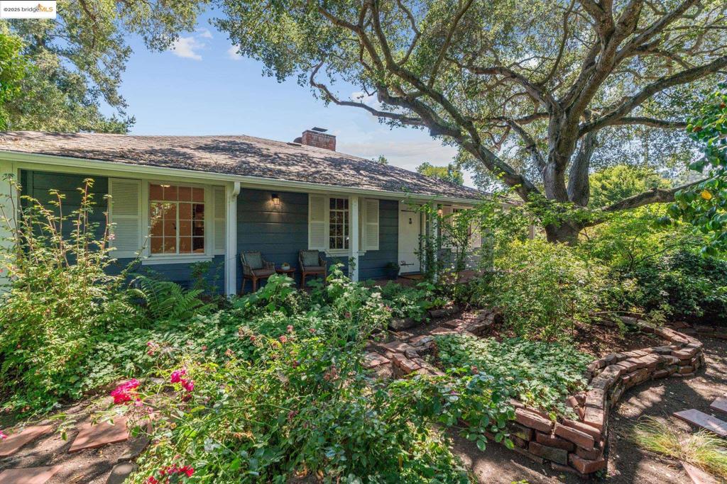 Spacious 1937 garden cottage in a magical, private park like setting. Custom original woodwork meets thoroughly modern updates in this enchanting one-level home. So many secret nooks, crannies and hidden features to discover! A wide covered brick porch sits beneath the massive oak which provides shade for the mature landscaped gardens. The handsome wood-paneled living room features a soaring brick fireplace flanked by built-ins. A formal dining room with built-ins looks out to the side garden and opens to the kitchen and large sunny family room. Two en-suite bedroom/baths include a large primary suite with huge walk-in closets. The primary bath features a wooden sauna and handy utility closet. The family room shares a breakfast bar with the kitchen and opens to the deck, fruit orchard and veggie boxes. The bonus space has a separate entrance and has provided a variety of uses over the years. It looks out to the rear garden and sits behind the 2-car garage. House heating and hot water are provided by a state-of-the-art heat pump by Harvest Thermal Systems. Solar panels are owned and the structure is seismically retrofitted. Only two blocks from busy Montclair Village shops with hiking trails and transport nearby. Feel the relaxing romance of the 30's while living a modern dream!
