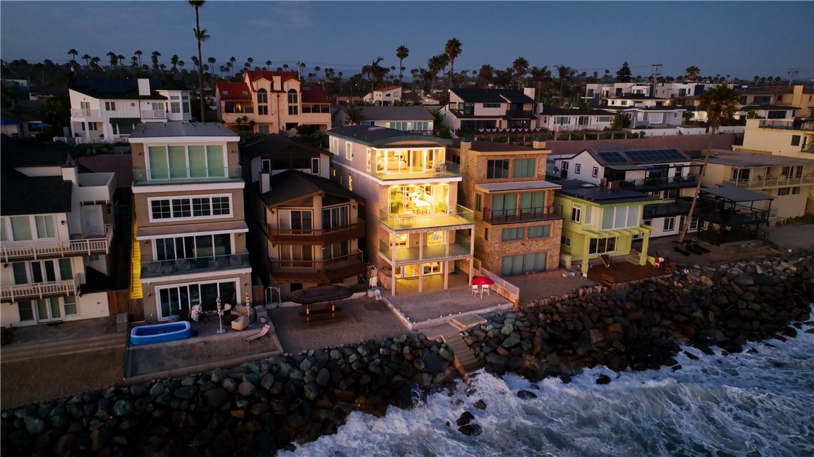 Located along the pristine shores of Oceanside Ca, this 3543 sq. ft. 3 bedroom/ 5 bath is an architectural masterpiece with the perfect balance of sophisticated elegance meets casual coastal living. The breathtaking expansive views of the Pacific Ocean can be taken in from any one of the four private terraces. The natural light floods in through the floor to ceiling windows creating a seamless transition between the indoor and outdoor spaces. Originally constructed in 1978 and completely redesigned and renovated with great care and attention to detail in 2015. Each of the four floors has their own unique features and amenities that will astound you!
The top floor is fully dedicated as the primary suite. The barrel vault wood ceiling throughout is breathtaking. First is the primary office for two with walnut built-ins and a private street deck. Next is the expansive spa like bathroom with heated floor, steam shower, dual sink vanity, soaking tub. This bathroom is what dreams are made of. The privacy sliding wood panels above the bathroom vanity when opened award you with those amazing ocean views. There is a large walk-in closet and storage built ins. Then comes the opulent primary suite with fireplace and reading nook with custom automated shades with blackout feature. You literally can walk onto your private deck to have your morning coffee!
The main floor is an open concept living area with high end kitchen appliances & custom walnut breakfast bar, book matched cabinets and Brazilian cherry floors. There is an expansive cement fireplace, bar area with stream-bed granite, wine fridge and under counter storage. The next floor has 2 bedrooms, 2 bath & an open loft. The 2 bedrooms have access to ocean views & the private terrace. One bedroom is an ensuite with private bath. The bottom floor leads out to the private beach and stairs leading down to the ocean. This floor is like a studio apartment with full gourmet kitchen and living area. It could be considered a separate living space from the rest of the home with minor alterations.There are outside stairs that lead to the private beach and outdoor shower.
Oceanside is a vibrant, hip and rich coastal community that offers so much including great coffee shops, amazing dining and shopping. Oceanside is the home to The Museum of Art, Pier Amphitheatre, & the Oceanside Mission. You are not just investing in this amazing home, you will be investing in a great coastal community!