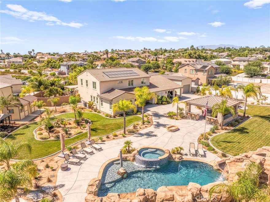 Experience unparalleled luxury in the prestigious Estate Collection at Woodcrest.

This sprawling 6-bedroom, 4-bath residence sits on just under an acre in one of Riverside’s most sought-after communities. The downstairs primary suite offers a serene retreat with a spa-inspired ensuite bath and a custom walk-in closet featuring built-in shelving and a glass-topped island display. Upstairs, a spacious loft and four additional bedrooms—including two that share a Jack-and-Jill bath—provide the perfect layout for family living. A private downstairs office offers a quiet workspace for remote professionals.

Thoughtfully upgraded throughout, the home features a Klipsch® home theater system, whole-house Waterboy® filtration, smart Lorex® security, and owned SunPower® solar panels for energy efficiency.

Step outside to your private resort—an entertainer’s paradise designed for year-round enjoyment. The PebbleTec® saltwater pool and spa shimmer under the California sun, accented by three cascading waterfalls and a built-in slide. A freestanding pavilion anchors the backyard with a designer outdoor kitchen and bar, complete with a pizza oven, built-in BBQ, sink, refrigerator, multiple TVs, ceiling fans, and surround sound. Whether hosting lively gatherings or relaxing poolside, this space delivers the ultimate in outdoor living.

The grounds also feature a basketball half-court (pickleball-ready), a dedicated play area with a wooden swing set, a cozy wood-burning fire pit, and professionally designed landscaping that blends lush greenery with elegant hardscaping. EverLights® LED architectural lighting enhances the home’s evening ambiance, creating a warm, sophisticated glow.

A custom RV garage, dual two-car garages, and a fully fenced property with block and wrought-iron detailing offer both functionality and privacy. This property is what new construction strives to be—crafted with quality, design, and distinction that only time and thoughtful upgrades can achieve. From its resort-style amenities to its refined interiors, this extraordinary estate embodies the best of luxury living in Woodcrest. Be sure to view the virtual tour to fully appreciate every remarkable aspect of this property.