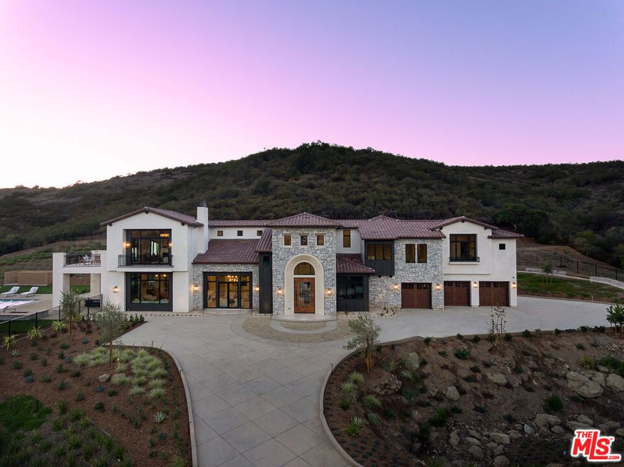 Set behind a private, gated driveway on 2.1 acres of pristine hillside, the residence captures sweeping, unobstructed canyon andsunset viewsthat overlook COSCA-protected open space, ensuring that its tranquil vistas will remain forever undeveloped. The architecture blends timeless European inspiration with the relaxed ease of California luxury. A stone-and-smooth-stucco facade introduces soaring ceilings, a grand entrance, with sunlight that spills acrosstravertine tile floors. The formal entry reveals a sweeping staircase and leads into elegant living spaces; a refined formal living room with fireplace and chandelier, formal dining room that opens to an interior courtyard with handcrafted fountain, and an open-concept family room framed by floor-to-ceiling glass and custom millwork. At the heart of the home lies a designerchef's kitchenappointed with quartz countertops, custom cabinetry, and professional-grade Wolf, Sub-Zero, and Bosch appliances, complemented by a Thermador wine column. Every major room is accented by California Faucets fixtures, while elegant wood floors bring warmth, texture, and timeless sophistication throughout. Offering five spacious bedrooms and five-and-a-half baths, including a serene primary suite retreat with large private balcony, the home also features a versatile office studio ideal for work, wellness, or creative pursuits. Outside, the resort-style grounds mirror the home's refined calm, a sparkling pool and spa, and dual-island outdoor kitchen overlook rolling hills, framed by manicured landscaping and multiple terraces for lounging or entertaining. The property's setting strikes the perfect balance of privacy and convenience: it's surrounded by nature yet moments from the upscale shopping, dining, and community life of Westlake Village and Calabasas. This newly constructed Westlake Village estate offers elegance and sophistication without the LA City mansion tax. Families will appreciate the home's location within top-rated school districts just a 15-minute scenic trail walk to Westlake Elementary, and minutes from Oaks Christian School.  Impeccably built, ideally located, and naturally secluded, this residence defines elevated living where architectural grace meets enduring privacy and the very best of Westlake Village luxury.