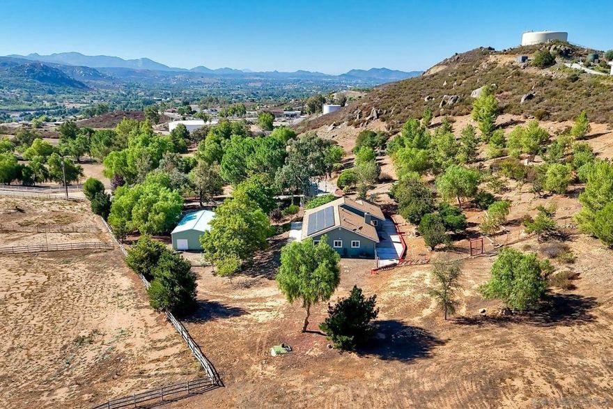 Discover this beautifully remodeled ranch-style retreat sits that on over 4 acres with direct access to thousands of acres of Cleveland National Forest, offering privacy, breathtaking views, and endless trails for hiking or horseback riding, including one to a nearby waterfall. The property features a 36 ft x 24 ft heated and insulated steel building with 100-amp service. The home blends modern luxury with self-sufficient living, featuring 100% waterproof luxury vinyl and stone tile flooring, a brick fireplace, and updated kitchen with stainless steel appliances. Both bathrooms have been fully renovated, new windows throughout, new roof and new exterior paint ensure energy efficiency and long-lasting quality. The property is connected to the grid and the owned 36-panel solar system currently generates 160% of the home's electricity, backed by an automatically switched 27 kW whole-house generator connected to a 500-gallon propane tank. New well pump and a 5,000-gallon holding tank. Outside, enjoy multiple patios, a 35-tree fruit orchard on drip with a varieties, mature shade trees, a Jacuzzi, infrared sauna, 240 sq ft chicken coop, RV hook-ups, and a fire safety system with hydrant, pump, 7,000 gallon storage tank and clear defensible space. Bonus features include the 36 ft x 24 ft steel building, a John Deere tractor, Yamaha Rhino 450, 5 cords of firewood, gun safe, huge fenced area for dogs and the property backs up to Cleveland National Forest. With 400 amps of power and plenty of room to expand, this property offers unmatched freedom and functionality.