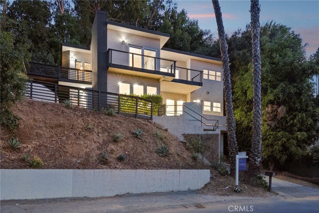 Flooded with natural light and framed by expansive windows, this Hollywood Hills residence offers a rare combination of privacy, space, and city views. The main level features a bright open living area with a sleek fireplace, an updated kitchen with granite counters, stainless steel appliances, and a center island, plus two bedrooms and a full bath. Upstairs, a luxurious primary suite spans nearly the entire level with spa-inspired bath, generous closet space, and direct access to a balcony showcasing sweeping canyon, mountain, and city-light vistas. Additional rooms provide flexibility for guest accommodations, office, or creative space, while multiple decks and terraces create seamless indoor-outdoor flow. Set in a quiet hillside pocket just minutes from Mulholland, studios, and the heart of Los Angeles, this home delivers the lifestyle of a private retreat with the convenience of city living.