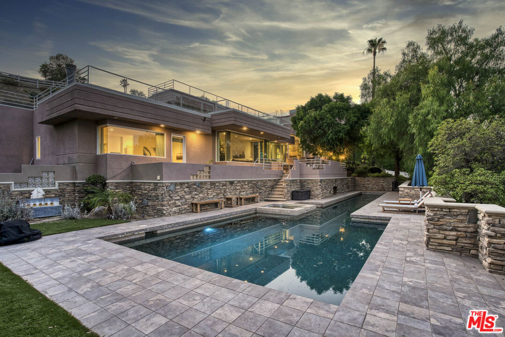 Perched at the end of a long private driveway in the prestigious guard-gated community of Bell Canyon, this striking architectural contemporary home blends privacy, luxury, and sweeping hillside and valley views from nearly every room. Set on over an acre of landscaped grounds, the property offers an exceptional backdrop for both everyday living and grand-scale entertaining. The impressive double-door entry opens to a light-filled multilevel floor plan, where glass, skylights, and soaring ceilings create a sense of openness and connection to the outdoors. Oversized living and dining areas flow seamlessly together, anchored by a dramatic two-sided fireplace and surrounded by view-filled patios. The chef's kitchen boasts Merle wood cabinetry, granite counters, dual islands, a breakfast bar, and an inviting eat-in nook with serene hillside vistas. A large family room overlooking the pool and patio features a pool table area and connects to a granite-topped wet bar with a mini-fridge that is perfectly placed for hosting guests. A highlight of the home is the private stadium-seating theater, offering the ultimate cinematic experience without ever leaving your property. For quieter moments, retreat to the private luxurious primary suite, complete with a fireplace, patio access, dual walk-in closets, and a huge spa-like bath featuring travertine finishes, a jetted tub, sauna, and separate vanities. The upstairs level includes a massive bedroom with a walk-in closet, a second large bedroom, and a shared Jack-and-Jill bath with dual vanities and an oversized soaking tub and makeup counter. Two additional main-level guest suites with en-suite baths provide flexibility for extended family or visitors. The resort-style front yard is a true showstopper, featuring a sparkling Pebble Tec lap pool with spa and grotto viewing window, expansive patios, a BBQ center, and rolling lawn areas - perfect for making memories with family and friends. Speakers in every room and outdoors are connected to Sonos, letting you set the perfect soundtrack for any occasion. A viewing area up behind the house is a perfect spot for taking in the incredible views. A mirrored 5-car garage provides the perfect setting for the car enthusiast, as well as ample parking up the long private driveway. Residents of Bell Canyon enjoy access to an equestrian center, clubhouse, gym, tennis and pickleball courts, hiking trails, and year-round community events - all within the award-winning Las Virgenes School District.