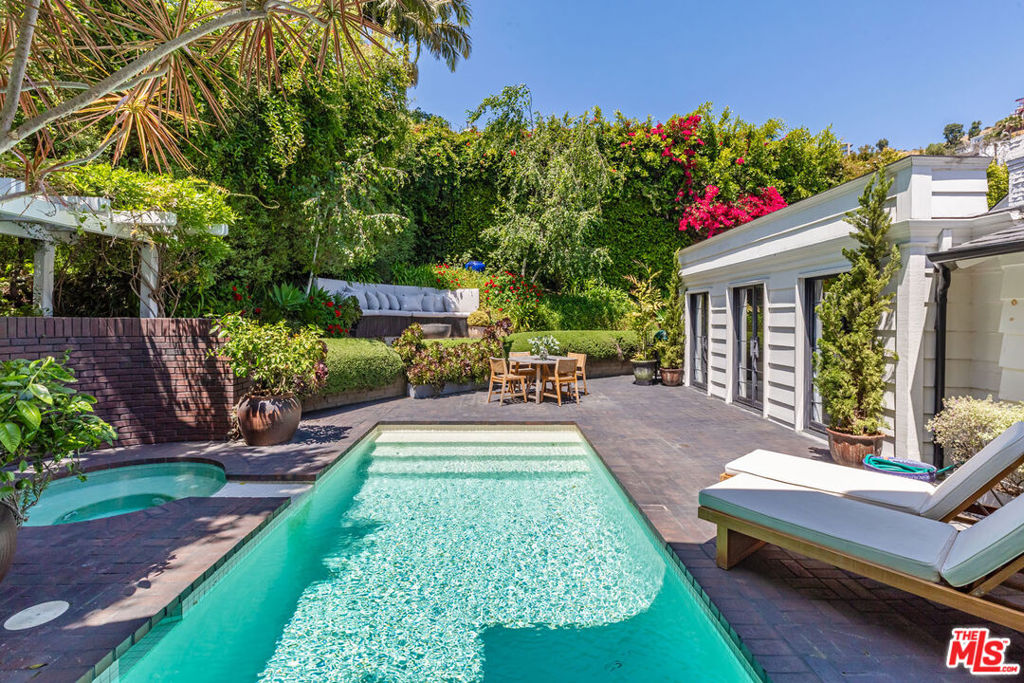 Charming lower Sunset Plaza jewel-box residence, originally envisioned by Robert Byrd AIA and thoughtfully reimagined by Bradley Adcock. Privately tucked away at the end of a cul-de-sac, the home sits behind a gated drive with a spacious motor court, offering serenity just minutes from the Sunset Strip. Inside, you will find refined details throughout - oak herringbone floors, French doors, picture windows filling the rooms with light, striking stonework, marble fireplaces, and inviting spaces ideal for entertaining. The main level boasts dual living rooms with soaring ceilings, an elevated formal dining area, a richly hued media room, and a bespoke bar. A spiral staircase from the curved kitchen descends to a hidden, prohibition-inspired wine cellar and tasting room. Occupying an entire floor, the primary suite impresses with 16-foot vaulted ceilings and a marble-clad bath overlooking the city. Outdoors, lush gardens surround the pool, spa, fire pit, and multiple sitting areas, creating a peaceful retreat. This one of a kind mini-compound offers a private oasis in the very heart of Los Angeles.
