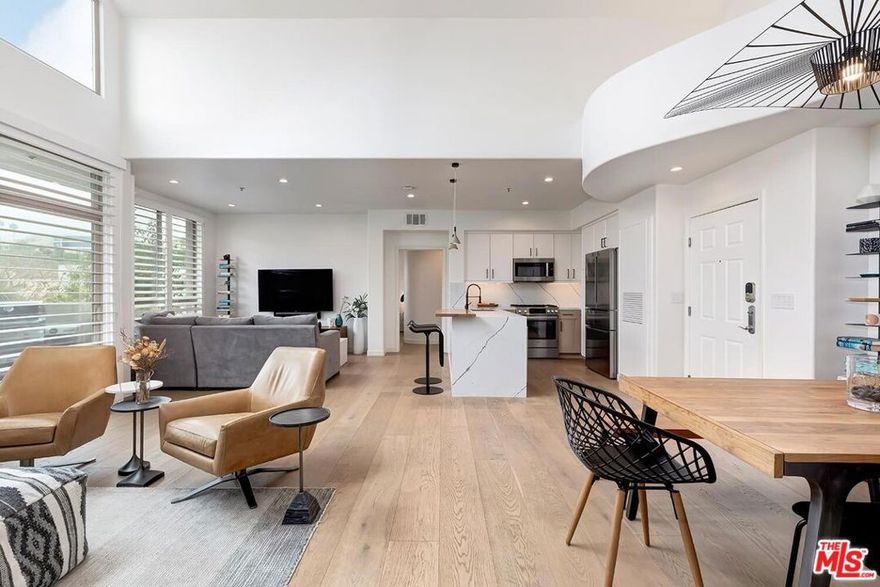 This exceptional 2-bedroom, 2-bathroom top-floor condo in the vibrant heart of Playa Vista is characterized by its soaring ceilings and abundant natural light. East-facing and sun-drenched, this unique unit features 20ft high ceilings, creating an open, airy ambiance. The thoughtfully crafted single-level layout ensures optimal space, with the bedrooms located on opposite sides of the unit. Large windows throughout enhance the home with natural light, and the roomy balcony provides scenic views of Concert Park extending to LMU. The recently upgraded kitchen is a highlight, complete with custom cabinetry, an island and bar seating, high-end stainless steel appliances, and modern finishes, making it perfect for cooking, entertaining, or unwinding at home. Additional features include designer lighting fixtures, fully integrated smart home controls, wide-oak plank hardwood floors throughout, central heating and air conditioning with a Nest thermostat, in-unit laundry, and two dedicated parking spots. Situated in The Promenade, this residence is just steps away from Playa Vista's finest amenities, such as Whole Foods, shops, restaurants, theaters, fitness centers, resort-style pools, and Playa Vista Elementary. This is a unique opportunity to own a bright, top-floor home in one of the Westside's most lively and well-connected communities.