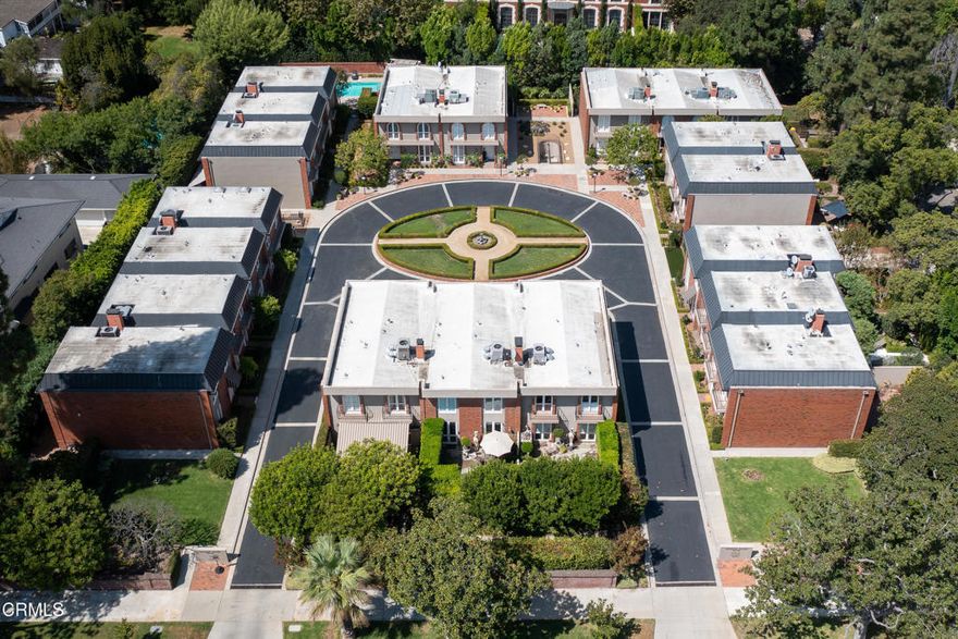 Sophisticated living within Pasadena's desirable Craven's Court along famed Millionaire's Row, this exceptional end-unit residence boasts one of the most coveted floor plans in the enclave, offering both scale and privacy with only one shared wall. From the moment you arrive, the frosted glass double-door entry welcomes natural light into a refined interior where herringbone hardwood floors, recessed lighting, and thoughtful details set the tone. Just off the entry, a versatile bedroom or office space with a closet and an adjacent guest bath provides function and flexibility. The main level flows seamlessly with a stylish wet bar connecting to the gourmet galley kitchen, featuring stone countertops, custom tile backsplash, a Zephyr range hood, JennAir refrigerator, and the kitchen's centerpiece, a Bertazzoni 5-burner cooktop and oven, regarded as the 'Ferrari' of ranges imported from Italy. A swinging door opens to the dining area, continuing into the spacious living room with crown molding, a fireplace, and direct access to a tranquil private patio with lush greenery and the soothing sound of a fountain. Upstairs, both bedrooms are private suites. The guest suite includes French doors with louvered shutters opening to dual balconies overlooking the patio, generous closet space, and a stone-topped vanity in the ensuite. Across the landing, the primary suite offers crown molding, custom built-ins, abundant closet space, and a spa-like bath with a stone vanity, a glass-enclosed shower, and luxurious finishes. Additional conveniences include a laundry closet, attic storage, and hidden retractable screens throughout. Residents of Craven's Court enjoy a gated pool, lushly landscaped grounds, and a circular driveway that evokes timeless Pasadena elegance. Combining the feel of a private retreat with proximity to the heart of Pasadena, this rare end-unit offers refined living along one of the most storied boulevards in Southern California.