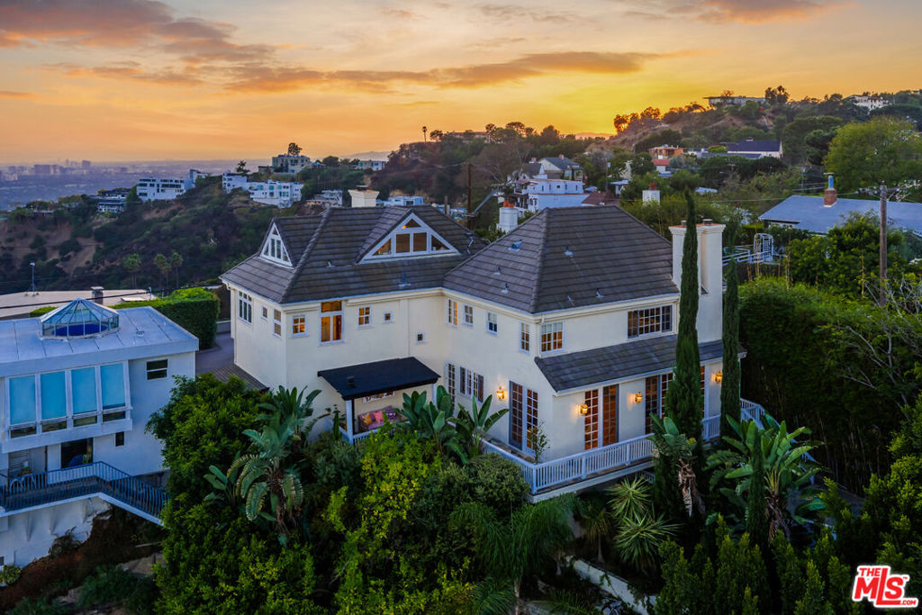 Perched high in the Hollywood Hills West, on a celebrity lined street, this private apx 4,000 sq ft hillside retreat offers modern sophistication with sweeping views of the city, mountains, and the iconic Hollywood sign - just minutes from the flats of West Hollywood, the legendary Sunset Strip, Studio City, and close to everything of interest. A dramatic entry courtyard, complete with Italian Cypress, lavender, and a custom fountain, sets the stage. Inside, soaring 14-foot ceilings and designer details - including Fornasetti and Scalamandre wall-coverings, Ralph Lauren and Jonathan Adler lighting throughout, oak floors, and George Nelson pendants - create a refined yet inviting atmosphere. The open living and dining areas flow seamlessly to expansive terraces designed for entertaining. A chef's kitchen boasts a glass-door Sub-Zero refrigerator, Viking appliances, and generous counter space. Multiple outdoor dining and lounging areas are enhanced by a fireplace, outdoor kitchen, and fruiting lemon trees. Three spacious ensuite bedrooms each feature walk-in closets and stunning views. Dual primary suites offer fireplaces, steam showers, and private balconies, while a separate staircase leads to a third ensuite bedroom and a custom loft. A den/screening room with surround sound and fireplace completes the interior. Outdoors, meandering stone pathways lead to a half basketball court under custom lighting - perfect for recreation or gatherings. A two-car garage, natural light throughout, and layered landscaping enhance this hillside oasis. Located within the award-winning Wonderland School District, this property offers privacy, style, and an entertainer's dream setting in the heart of the Hollywood Hills.