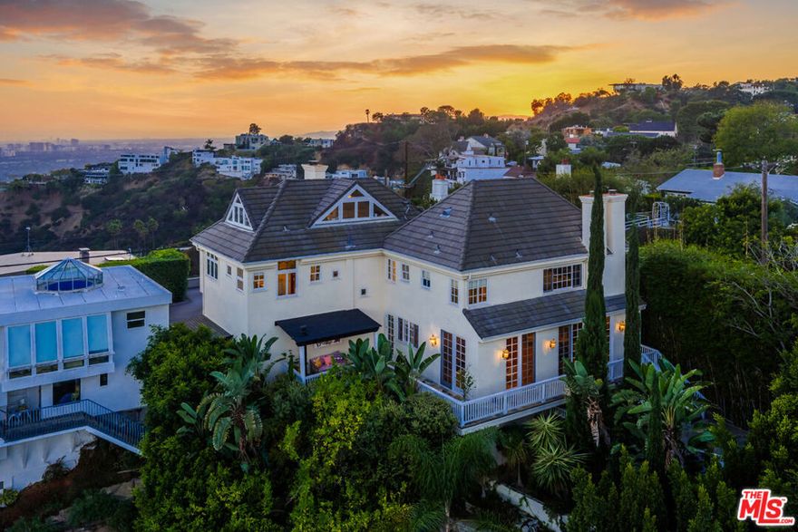 Perched high in the Hollywood Hills West, on a celebrity lined street, this private apx 4,000 sq ft hillside retreat offers modern sophistication with sweeping views of the city, mountains, and the iconic Hollywood sign - just minutes from the flats of West Hollywood, the legendary Sunset Strip, Studio City, and close to everything of interest. A dramatic entry courtyard, complete with Italian Cypress, lavender, and a custom fountain, sets the stage. Inside, soaring 14-foot ceilings and designer details - including Fornasetti and Scalamandre wall-coverings, Ralph Lauren and Jonathan Adler lighting throughout, oak floors, and George Nelson pendants - create a refined yet inviting atmosphere. The open living and dining areas flow seamlessly to expansive terraces designed for entertaining. A chef's kitchen boasts a glass-door Sub-Zero refrigerator, Viking appliances, and generous counter space. Multiple outdoor dining and lounging areas are enhanced by a fireplace, outdoor kitchen, and fruiting lemon trees. Three spacious ensuite bedrooms each feature walk-in closets and stunning views. Dual primary suites offer fireplaces, steam showers, and private balconies, while a separate staircase leads to a third ensuite bedroom and a custom loft. A den/screening room with surround sound and fireplace completes the interior. Outdoors, meandering stone pathways lead to a half basketball court under custom lighting - perfect for recreation or gatherings. A two-car garage, natural light throughout, and layered landscaping enhance this hillside oasis. Located within the award-winning Wonderland School District, this property offers privacy, style, and an entertainer's dream setting in the heart of the Hollywood Hills.