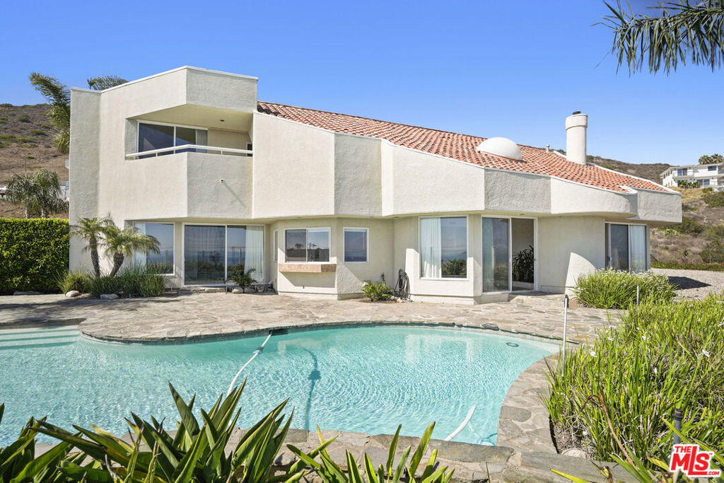 Perched directly across and above El Matador Beach, this light-filled two-story architectural home showcases breathtaking panoramic ocean and whitewater views from every room. Designed and meticulously maintained by its architect-owner, the residence offers 4 en-suite bedrooms and 5 bathrooms, including an expansive primary suite with fireplace, two private balconies, spa-style bath with oversized shower, dual sinks, and four closets. A vibrant atrium with a soothing fountain sets the tone for the open-concept layout, featuring soaring ceilings and walls of glass that bring the outdoors in. The Chef's kitchen with teak cabinetry, double ovens, sinks, dishwashers, and a wine fridge, offer stunning coastline views. Perfect for entertainment, the home includes a large pool, spa, patio and a gated motor court with a 3-car garage. This gated and fenced property offers ample space for pets and play. Designed to take full advantage of the dramatic topography and sweeping vistas, this unique Malibu gem embodies the very best of coastal living.