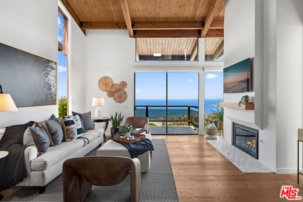 Sweeping coastline, ocean, and city light views set the backdrop for this newly redesigned soft-contemporary home with dramatic mid-century modern flair, perched at the crest of Laguna Beach's coveted Arch Beach Heights. Spanning approximately 2,373 square feet across three levels and a mezzanine, the home features four bedrooms and five updated bathrooms --three full and two half-- offering optimal flexibility with at least one on each floor. The light-filled living room showcases vaulted ceilings, a sleek fireplace, floor-to-ceiling windows, and balcony that seamlessly connects indoor and outdoor living while showcasing the California coastline. The adjacent dining area flows into a chef's kitchen outfitted with Wolf and Sub-Zero appliances, quartz countertops, white Shaker cabinetry, and a peninsula with a farmhouse sink. The kitchen and dining area are strategically elevated two steps to maximize views from all main living spaces. A striking mid-century mezzanine above the kitchen creates a dramatic visual when viewed from the living room and offers an ideal space for a home office with a view, as well as direct access to the garage. Notable upgrades include a brand-new roof, updated bathrooms, and a new electrical panel. The versatile bottom level, complete with a wet bar and wine refrigerator, can function as a media room, guest suite, fourth bedroom, or potential ADU, and opens to a perfectly sized backyard that still captures glimpses of the coastline. The ocean-view primary suite features a private deck, fireplace, three closets, and a spa-inspired bath with gold-tone fixtures and a rain shower. Additional highlights include central air conditioning, Lutron lighting and shade controls, two Level 2 EV charging outlets, Toto Washlet heated toilets throughout, home soft water system, under sink water filtration system, smart garage door with keypad access, and multiple outdoor spaces. Enjoy close proximity to Moulton Meadows Park, scenic hiking trails, tennis courts, and top-rated schools all just minutes from Laguna Beach's shops, galleries, and dining. Click Virtual Tour for 3D Matterport