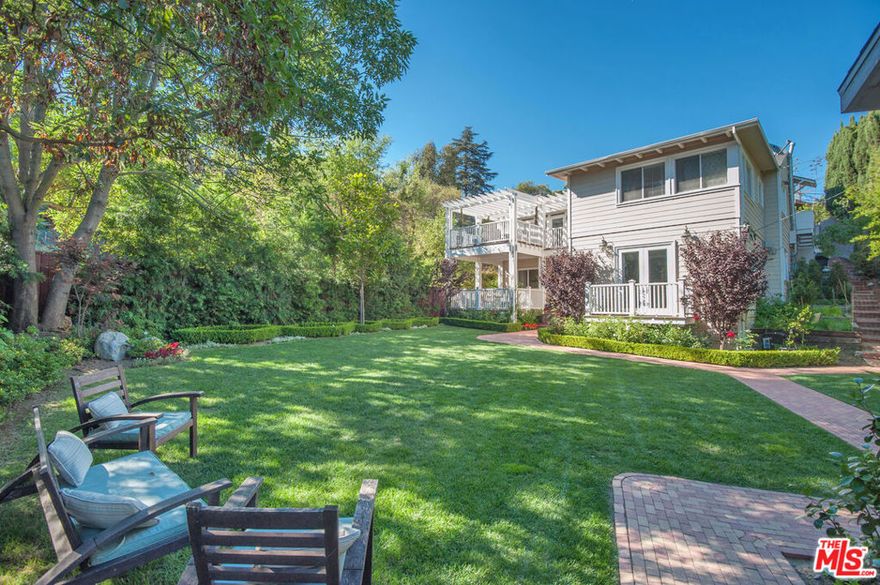 Experience tranquil hillside living in this beautifully updated home that blends timeless style with modern comfort. The interior features hardwood floors, recessed lighting, vaulted ceilings, skylights, and distinctive custom tilework throughout. The chef's kitchen is thoughtfully designed with handmade Italian tiles, a Thermador cooktop, wall-mounted pot filler, warming drawer, and ample storage. Bright living and dining areas open seamlessly to one of two expansive decks, ideal for outdoor dining and entertaining. The HGTV-inspired primary suite offers coved ceilings, custom closets, and a spa-like bath. Enjoy a large, flat grassy backyard with a peaceful, park-like setting and a tranquil waterfall nearby. Additional highlights include dual-zone HVAC, Pella windows and doors, a tankless water heater, a two-car garage with exceptional storage, and abundant street and off-street parking. Nestled on a quiet street off Mulholland, this private retreat feels immersed in nature while offering quick access to Hollywood, Studio City, Toluca Lake, and Universal City - truly the best of both worlds.