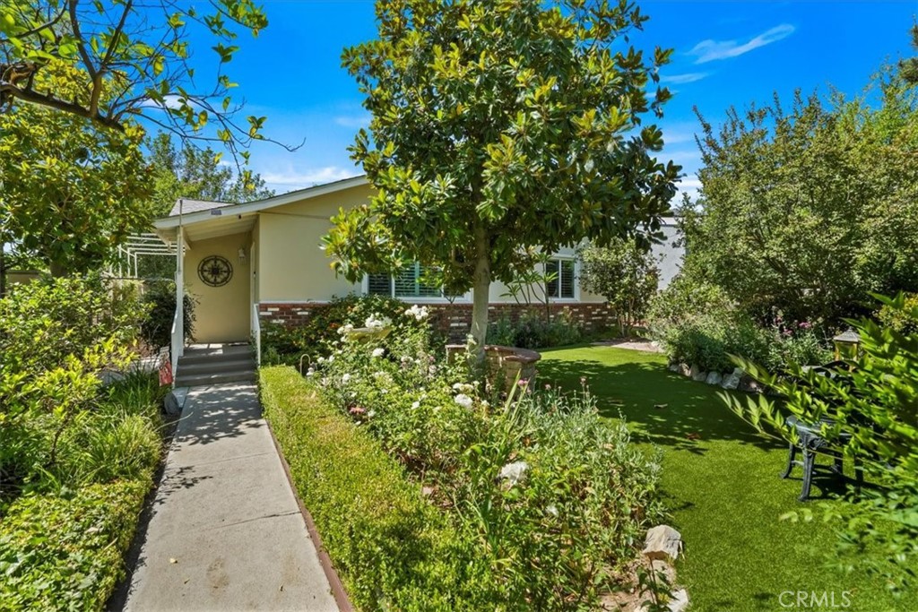 Welcome to your Secret Garden! Perched above the street sits this charming 2 bedroom, 1 bath retreat, nestled behind lush greenery for added privacy and tranquility. From the moment you arrive, you're greeted by a gated entrance and a beautifully landscaped front yard that feels like your own hidden oasis. Step inside to find a bright and inviting living space filled with natural light, newer flooring, shutters and thoughtful updates throughout. The kitchen features stainless steel appliances, plenty of storage with a great view of the lovely backyard. Perfect for home-cooked meals and entertaining. Out back, discover a huge backyard with mature fruit trees and vegetation and a covered patio ideal for lounging, BBQs or sipping your morning coffee in peace. Inside the gated backyard there is plenty of secured parking on the driveway or under the carport. There is also a double detached garage and additional parking area off of the alley. This huge lot offers plenty of options including the possibility of an ADU (Buyers to Investigate.) Conveniently located close to Veteran's Park, El Cariso Regional Park, L.A. Mission College and easy freeway access. Also just a short distance to great hiking, biking and horseback riding trails.