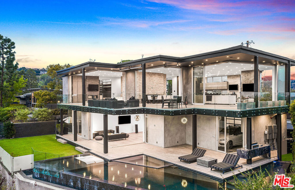 Perched at the end of a quiet cul-de-sac stands this custom modern trophy estate. Stunning views of DTLA, the coastline, and Crestwood Hills from every angle, as if you are floating on air. Designed around the art of entertaining, floor to ceiling glass panels seamlessly disappear & integrate the view, the outdoors, the wrap around deck and the interior space. This private oasis is truly a must see in person to experience the energy and privacy. A modern floor plan that features a large sleek fully equipped chefs kitchen, an oversized dining room & an enormous living room that overlooks the captivating views. The main suite rivals any 5-star hotel, with an oversized walk-in closet & spa like bathroom. The lower level consists of a gym, family room, glass wine room, & movie theater. Featuring 5 en-suite bedrooms and 8 baths laid out over 7,040 SF, a dramatic infinity pool, grassy pad and tons of space to bask in the sun and enjoy the So Cal weather. The ultimate modern view home.