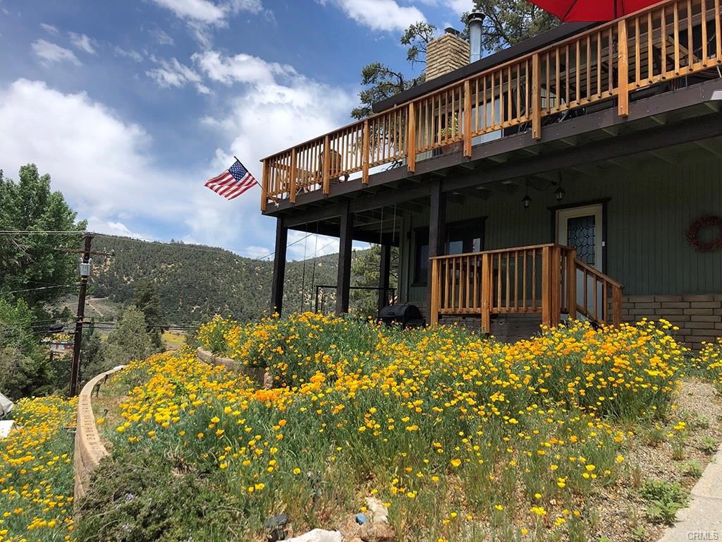 Custom 3+ bedroom, 2 bath home with panoramic views nestled on 1/3 acre of private, landscaped grounds in exclusive Pinon Pines. The views are maximized with a reverse floor plan featuring an open concept great room, wood vaulted ceiling, wood laminate floors, windows galore and an Elmira wood burning stove on a rustic stone hearth, flanked on both sides by window seat/wood boxes with outdoor access. The kitchen is an entertainers delight with stainless steel Viking and KitchenAid appliances, custom cabinets with glass uppers, pull-out lowers and lots of counter & storage space. The central dining area has natural light through sliding glass doors which lead to an 800sqft wrap-around deck opening the home up for outdoor living. The spacious master retreat has a vaulted ceiling and sliding glass doors to access the secluded, shady end of the deck. The main floor bathroom features a big jetted tub and double sinks. Also on the main floor is a bonus room with laundry, built in cabinets and a garden window. Downstairs is a beautifully remodeled full bath and two bedrooms, one with a walk-in closet and barn door. Storage abounds with an oversized, attached two car garage and separate garage/workshop totaling 900sqft of garage space. The property is attractively landscaped with Pinon Pines, an apple tree, drought resistant plants, lilacs, a big lawn and a fenced dog run. Enjoy cooler weather and cleaner air, less than an hour from Bakersfield and Santa Clarita Valley