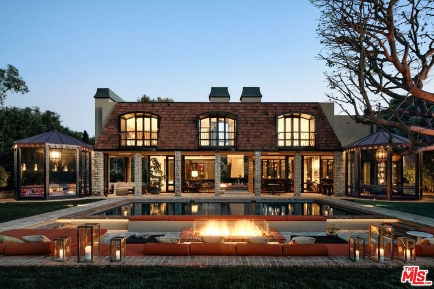 This Bel Air John Elgin Woolf-designed residence, his personal home, is one of his finest restored works. Known as the Father of Hollywood Regency, Woolf's iconic design is a key piece of LA architectural history. Jack Wolf masterfully blended traditional and modern design for a unique, glamorous style. Restored and reimagined by RIOS under Mark Rios FAIA FASLA and featured in Architectural Digest, this 8,400sf gem blends timeless elegance, fresh modern elements, bespoke upgrades and refined spaces for elevated living and entertaining. Set on nearly three-quarters of an acre behind private gates, soaring hedges and a large motor court, this thoughtfully designed home features 6 bedrooms, 6 bathrooms, 2 powder rooms and striking details like skylights, bold colors, mirrors and glass walls. Iconic Woolf elements in the oval windows and oversized Pullman doors preserve the home's original Hollywood Regency character. The soaring foyer with wood floors and floor-to-ceiling glass walls is flooded with natural light. At the heart of the home, a tranquil courtyard artfully divides the cocktail lounge from the Red Library Room. The spacious cocktail lounge features a sculptural fireplace, anchored by a custom floating black polished bar, built-in shelving, original sconces, sitting area and wraparound glass walls framing the grounds. The Red Library Room features a marble-clad fireplace, herringbone wood floors, bespoke built-ins and floor-to-ceiling shelving, complemented by a 100" TV home theater system for a cinematic experience. This wing also houses two elegantly appointed bedroom suites, each with unique design elements, including vibrant bathroom suites. A main floor third bedroom suite completes the sleeping quarters. The two-story formal dining room features expansive walls for art and an original Woolf antique mirrored ceiling with skylights. Signature Woolf elements, including the original mirrored dining table, anchor the space, preserving Hollywood Regency charm and elevating its grandeur. The sleek, all-black and stainless-steel gourmet kitchen pairs discreet Bulthaup cabinetry with top-tier appliances, an elongated wood butcher block island and a secondary working kitchen. The octagonal breakfast room opens into a glass-walled pavilion with custom cabinetry and serene views. Double doors lead to the swimming pool area with sunken living room, fire pit and Moroccan-inspired glass pavilion. Stone paths lead to a serene koi pond, complemented by a pavilion with outdoor kitchen. Inside, ascend the sculptural staircase, framed by glass walls to the primary suite sanctuary, where a balcony overlooks lush grounds, complemented by dual spa-inspired bathrooms and custom walk-in closets. One bathroom showcases bold black marble, textured wall coverings and a spacious closet, which connects to an adjoining bedroom suite (currently an office). The second bathroom dazzles with white marble, a custom Rios-designed stone soaking tub, a marble vanity and walk-in closet with chic dressing room and elevator. Additional amenities include a wine room, separate fully equipped gym with en-suite bathroom (can also function as a guest suite), house manager's office, utility room and a two-car garage, all enhanced by state-of-the-art integrated music, entertainment and lighting system. The property also offers a rare opportunity for an accessory building or ADU with a separate street entrance. This home presents a distinctive yet very comfortable way to live, offering refined living and tranquility within this exclusive enclave of Bel Air.