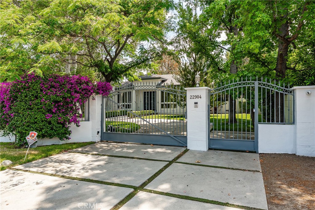 Walnut Acres completely remodeled and gated estate situated on a 27,000 SF flat lot! Privately set back from the street behind two automatic security gates, the front yard features a grand circular driveway plus separate long driveway that leads to the 3-car attached garage with direct access with room for ample parking/RV/boats. Step inside the double door entry into a grand foyer to find a completely open floor plan flooded with natural light, designer finishes, and wide plank polished wood floors found throughout. Interior spaces include oversized formal living room with large picture windows overlooking the front yard, separate formal dining area, and spacious family room with fireplace and French doors that lead out to the yard. The massive chef’s kitchen opens directly to all living spaces and boasts center island, quartz counters, stainless Thermador appliances, wine fridge, soft close cabinetry, walk-in pantry, and separate breakfast bar. There are 5 total bedrooms all en-suite with private bathrooms and custom closets with built-ins. The second level is dedicated to the sprawling and luxurious primary suite boasting well appointed bedroom with 2 large walk-in closets with built-ins, separate large sitting room with coffee bar with sink & fridge, French doors that open to a private covered balcony deck overlooking the grounds, and remodeled private bathroom featuring dual sinks, soaking tub, large walk-in shower, and separate toilet room. The four secondary bedrooms are located downstairs, one of which is extra large, ideal for downstairs primary bedroom or office/theater/gym. The entertainer’s backyard features pebble finished pool & spa, covered outdoor kitchen with sink, covered lounge seating area, lighted sports court with two basketball hoops, sprawling grass lawn, and gated side yard ideal for dog run. The first level also features a separate guest powder bathroom, large laundry room with sink & built-in cabinetry, and utility/camera room. Per seller: 3 HVAC systems, 2 water heaters, app controlled gate openers. Adjacent to dining/shopping at Westfield Mall & Village, Calabasas Commons, Warner Center & zoned for award-winning El Camino & Hale charter schools.