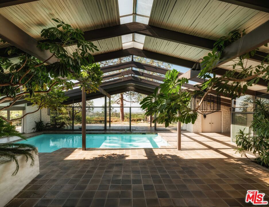 The Dr. Richard Henry House (1966) by Cliff May. Perched on a private 1.3-acre promontory in Lower Bel Air, this gated single-story estate is one of Cliff May's most discreet and rarely seen masterpieces. Preserved in its original condition, it presents a rare opportunity to restore or reimagine an unaltered example of his iconic California ranch style. Walls of glass frame uninterrupted panoramic views from Downtown Los Angeles to the Pacific Ocean, with the Getty Museum perfectly in sight. Inside, soaring post and beam ceilings, expansive skylights, and a striking indoor pool pavilion showcase Cliff May's seamless integration of architecture and landscape, where sunlight and greenery blur the lines between indoors and out.This is a rare chance to acquire a pristine Cliff May residence, an enduring piece of architectural history ready for its next chapter.