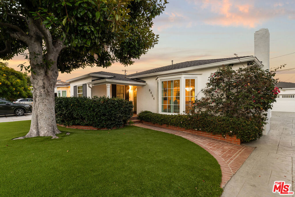 Welcome to 8454 Truxton Avenue, where classic Westchester charm meets effortless California living. From the moment you arrive, the inviting covered porch framed by a stately magnolia tree sets the tone for a home that's both warm and elegant. Step inside to a sunlit living room with a cozy fireplace and a bay window overlooking the beautifully landscaped front yard. The generous dining room flows seamlessly between the living and family rooms, creating an ideal space for gatherings large or small. At the heart of the home, the kitchen is both functional and stylish, boasting black granite countertops, crisp white cabinetry with a built-in secretary desk, newer appliances, a bay window above the sink, and a bright breakfast nook. The family room opens through French doors to the backyard, inviting indoor-outdoor living at its best - perfect for morning coffee, weekend BBQs, or evening cocktails under the stars. The backyard is a private retreat, featuring mature shade trees - including a striking Norfolk Island Pine - lush plantings, a grassy lawn, and a stamped concrete patio ready for alfresco dining, entertaining, or quiet afternoons soaking up the sun. Three spacious bedrooms are complemented by a remodeled bathroom with a step-in shower, separate soaking tub, and modern finishes, plus a convenient dual-entry half bath. Behind the detached two-car garage, a versatile bonus room with its own three-quarter bath is perfect for guests, a home office, or a creative studio. Ample garage storage and a long stamped concrete driveway provide plenty of parking for family and friends. Additional highlights include oak hardwood floors throughout, central air and heat, and a newer roof (2020), blending timeless quality with modern comfort. Nestled in one of Westchester's most desirable neighborhoods, 8454 Truxton Avenue offers a lifestyle of relaxed sophistication, effortless entertaining, and classic charm - a home you'll be proud to welcome friends and family to.
