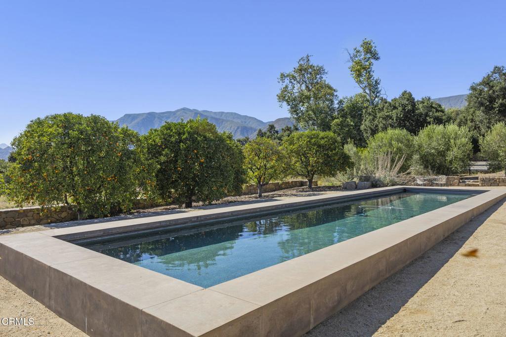 Tucked away in the esteemed East End of Ojai down a private drive adjacent to orchards and timeless stone walls sits this classic single story ranch home. With 1.25 acres of land adorned with avocados, citrus, apples, figs and an impressive lap pool this unique home features 3 bedrooms and 3 baths with over 2800 sq ft of living space. The generous high-ceilinged family room is enhanced with custom shelving and bookcases. Additional features include a central fireplace in the open concept living room, newer owned solar with two backup batteries and a private airstream perfect for overnight guests looking to escape the City life. This simple yet elevated modern home boasts views from every direction. If you are looking for a private oasis you will not want to miss this one of a kind property in the alluring East End of Ojai.