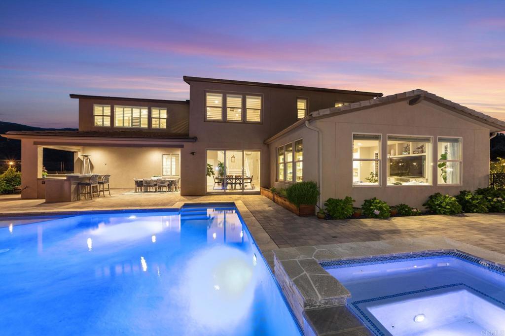 Welcome to your private, peaceful sanctuary with unparalleled mountain views from one of the most coveted lots in Harmony Grove Village! Set on an elevated premium 0.61-acre lot at the end of a cul-de-sac with just two houses on the cul-de-sac--providing unmatched privacy and space for relaxing and entertaining. Spanning 4,155 square feet, this 5-bedroom, 4.5-bathroom two-story home showcases luxurious design inside and out, a modern open, airy floorplan and extensive indoor-outdoor living. The backyard boasts a custom-designed saltwater pool and spa with waterfall, an outdoor kitchen with a built in BBQ and a Kamado Joe smoker, a large California room and patio area wired for a TV, a fire pit perfect for s’mores or warming up on cool nights, artificial turf side yard, a herb garden, raised vegetable beds and planters and over 10 fruit trees/bushes. Additional features include a fully owned 25-panel solar system, full drip irrigation with programmable control and a removable, locking pool safety fence for peace of mind. Main-Level Highlights Include: • Entertainers kitchen featuring stainless steel appliances (including double ovens), an oversized island with dual sided cabinetry (storage, storage, storage!), quartz countertops, butlers pantry, and walk in pantry with thoughtful, well designed custom cabinetry • Huge great room with tons of bright light, custom built-ins and gorgeous panoramic mountain views • Generous guest suite with private bath—perfect for visitors or multigenerational living • Grand front entry with soaring ceilings and natural light •Formal dining room• Dedicated office/library with large custom built ins (more extra storage!) •Eat in kitchen area with heavy duty double upgraded stacking doors• Additional den/flex room with extensive cabinetry and wine fridge, a custom functional mudroom with closets and direct access to a 3-car garage. Upstairs you’ll find an expansive primary suite with panoramic views, spa-inspired bathroom featuring upgraded tiling and mirrors, dual vanities, a soaking tub, oversized walk-in shower, and an impressive custom built walk-in closet • Generous loft for added living space • Two bedrooms with Jack-and-Jill bath with dual sinks • Additional full bathroom and an oversized bedroom/bonus room ideal for a playroom, gym or creative studio • Upstairs laundry room with upper & lower cabinetry, quartz counters, and LG washer/dryer included Additional home features and upgrades include: Upgraded flooring and tiling throughout • Custom built ins and closets throughout • Plantation shutters and custom window coverings • 220V EV charging outlet • Tankless water heater • Whole-house water filtration system • Two Quiet Cool whole house fans • Rain gutters • Stunning landscaping • Smart home tech: Arlo security cameras, Ecobee thermostats, and keyless entry Harmony Grove Village offers a rural, intimate neighborhood feel yet you’re mere minutes to modern conveniences, like dining, shopping, major medical centers, and top rated schools• Easy access to major highways makes commuting to San Diego or Orange County a breeze. • Miles of multi use trails • Heated Olympic-style pool and spa • Parks, playgrounds, dog park, and basketball courts • HOA community events that are fun for all ages • Evening security patrol. This is more than a home—it’s a lifestyle! Schedule a private tour and experience this rare Harmony Grove Village gem for yourself.
