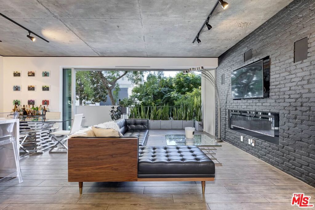 Photos are from previous listing and do not accurately represent condition of unit and/or furniture. Nestled in the prestigious Doheny Plaza, this fully reimagined residence offers a sophisticated retreat on the serene side of the building, overlooking the lush treetops of Norma Place. The thoughtfully designed open floor plan creates a seamless flow between expansive living spaces, anchored by a spacious living room that opens to a sunlit balcony through floor-to-ceiling pocket doors. The chef's kitchen is a showpiece, featuring a waterfall-edge island, Italian Carrera marble countertops, and sleek cabinetry. Designer touches throughout include exposed brick, wood-look tile flooring, polished concrete ceilings, and spa-like marble bathrooms. The primary suite offers a tranquil escape with blackout shades and a generous custom walk-in closet. Smart home upgrades include Lutron lighting and a Nest thermostat for modern convenience. Positioned at the crossroads of Beverly Hills and West Hollywood, Doheny Plaza places you moments from premier dining, shopping, and entertainment. This full-service building offers 24/7 doorman and valet service, on-site management, a heated pool with cabanas, an exercise room, and secure gated parking with up to two assigned spaces.
