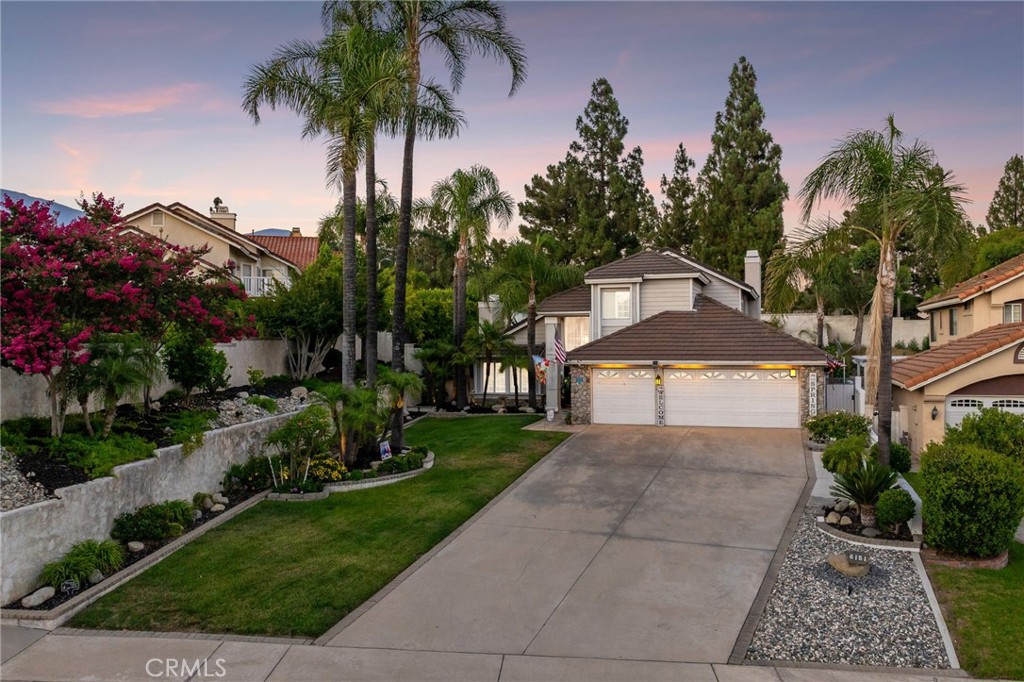 Remodeled Pool Home with Stunning Curb Appeal and Expansive Backyard. Welcome to this beautifully remodeled pool home nestled on a deep lot, offering exceptional curb appeal and refined living both inside and out. The front yard showcases lush green grass, manicured planters, an elevated retaining wall, soaring queen palms, a rock garden, and river rock accents that enhance the home's exterior charm. A custom concrete walkway leads to a welcoming covered porch with elegant iron and glass double entry doors. Step inside to travertine tile flooring and an impressive sweeping staircase that sets the tone for the rest of the home. The formal living room features vaulted ceilings, a custom fireplace, and a dramatic picture window that frames views of the beautifully landscaped front yard. Adjacent is the formal dining room, complete with a chandelier and plantation-shuttered window overlooking the backyard—perfect for entertaining. The updated kitchen is a chef’s delight, featuring classic white cabinetry, granite countertops, a tile backsplash, recessed lighting, a sunny breakfast nook, and peninsula seating that opens seamlessly to the family room. The family room continues the flow with travertine flooring, a striking river rock fireplace, built-in cabinetry, and sliding glass doors that lead to the private backyard oasis. Downstairs also includes a well-appointed bedroom and a bathroom with a frameless glass shower—ideal for guests or multigenerational living. A spacious laundry room offers direct access to the three-car garage. Upstairs, the spacious primary suite impresses with vaulted ceilings, sliding doors to a private view balcony with sweeping neighborhood and mountain views, and a spa-like bathroom featuring dual sinks, a makeup vanity, a custom tiled shower with frameless glass, and a separate soaking tub. A generous walk-in closet with mirrored doors completes the retreat. Two additional upstairs bedrooms share a Jack and Jill bathroom with dual sinks and updated finishes. Step outside to a resort-style backyard designed for relaxation and entertaining. Enjoy a sparkling pool and spa, covered patio, expansive concrete decking, fire pit, artificial turf, and beautifully landscaped grounds—all surrounded by privacy-enhancing stucco walls. This turnkey residence combines elegant design, thoughtful upgrades, and incredible outdoor amenities—an exceptional opportunity in a prime location.