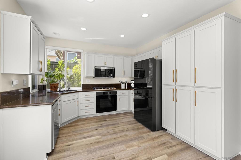 Located within the Poway Unified School District, this stunning 4-bedroom, 3-bath home offers comfort, style, and privacy. No Mello-Roos and a low HOA fee. A rare layout includes a first-floor bedroom and full bath. Soaring vaulted ceilings and abundant natural light create an airy, inviting atmosphere. The kitchen cabinetry has been tastefully refinished, with soft-close hinges and sleek new hardware. The kitchen also offers premium appliances, while the bathrooms include refinished cabinetry, updated lighting, new vanity mirrors, and upgraded toilets. Additional upgrades include new flooring throughout, recessed lighting, motorized shades, fresh paint, upgraded light fixtures, and custom closet organizers.The private backyard backs to a greenbelt and features succulents, drought-tolerant landscaping, upgraded concrete work, and custom garden beds. Privacy trees line both side yards, creating a secluded feel.The home also features an updated laundry area with a countertop, shiplap backsplash, and an automatic exhaust fan. The garage is fully finished with custom cabinetry, a workbench, and upgraded flooring. Situated within walking distance to the neighborhood elementary school.