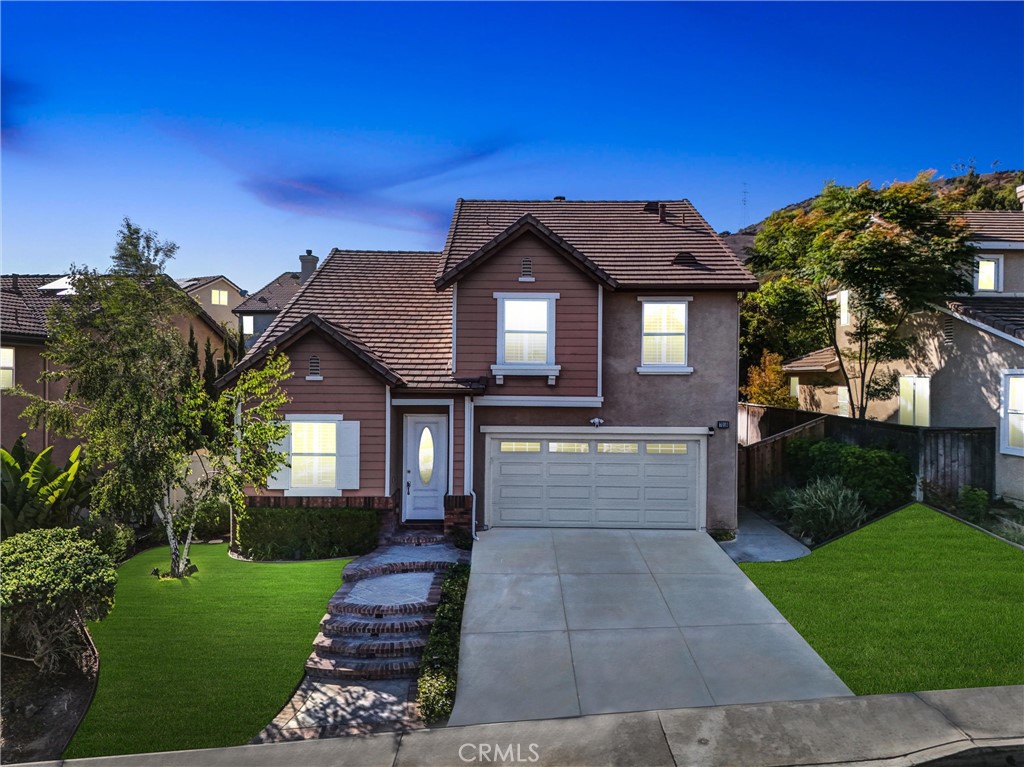 Nestled in the serene and highly sought-after Serrano Heights community, this stunning PLAN 3 residence is one of the largest and most desirable floor plans in the tract. Surrounded by lush landscaping, scenic hills, and nearby parks, the home offers unmatched curb appeal with fresh paint inside and out, new front and backyard lighting, sprinklers, and beautifully updated landscaping. Step inside to discover a bright and welcoming foyer that opens to elegant formal living and dining rooms, flowing seamlessly into a cozy family room with a warm fireplace. The gourmet kitchen is a chef’s dream, featuring granite countertops, and a sleek black granite double sink. The adjacent dining area overlooks a private, park-like backyard—perfect for relaxing or entertaining. A first-floor bedroom and full bathroom offer ideal accommodations for guests or multi-generational living. Upstairs, the expansive primary suite boasts a spa-inspired updated bathroom and generous closet space, accompanied by two additional bedrooms, a full bath, and a conveniently located laundry room. A spacious third-floor loft adds even more flexibility—ideal for an office, playroom, or media room—with potential to convert to a five-bedroom layout. Outdoors, enjoy al fresco dining at the built-in gas BBQ with counter-bar, surrounded by mature trees and lush greenery. The attached two-car garage offers ample storage, and the location provides easy access to top-rated schools, shops, freeways, toll roads, and natural escapes like Santiago Oaks Regional Park, Oak Canyon Nature Center, and Walnut Canyon Reservoir. This is Southern California living at its finest.