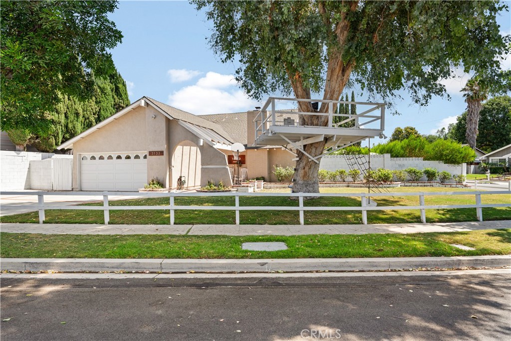 Situated on a sweeping corner lot, this beautiful traditional style home has all the charm you could want! Enclosed by a custom wraparound farm house post and rail fence, the grassy play yard features a giant eucalyptus tree with custom treehouse — a dream for kids! A soaring two story ceiling entry greets you as you enter the light and bright living space, updated with rich dark engineered wood floors throughout. Large open paned windows showcase the entertainer’s backyard and mature landscaping, sparking your imagination for the next party. The living room centers on a white brick fireplace embellished with a dark wood beam mantle and large windows with custom black curtain rods and white linen drapery. The updated kitchen offers quartz countertops, white cabinets, electric stainless steel appliances and a large custom wood top center island with additional seating — perfect for casual dining and gathering. The versatile floor plan features three bedrooms down (one of them ensuite) and one bedroom and bathroom upstairs that can serve as a private primary suite or a secluded guest retreat. Adjoining the upstairs bedroom and updated bath is a large loft, ideal for a playroom, home office or separate family room. Outside, a large covered patio is perfect for entertaining, BBQing and enjoying the mature green-leaf Dodonea trees that create a private, lush backdrop. The large grassy backyard and a custom-built batting/pitching cage in the side yard offer endless possibilities for fun and recreation. Don’t miss this exceptional home where timeless character meets modern updates.