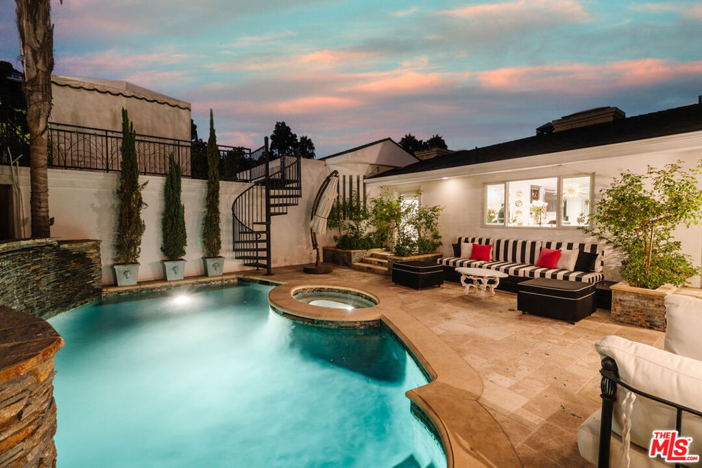 Located just above the world-renowned Sunset Strip and adjacent to the highly coveted Bird Streets of Hollywood Hills West, this impeccable, freshly updated Mediterranean-inspired residence offers striking city views and awaits its fortunate new owner. Enter into the welcoming foyer to discover a lifestyle of chic opulence and a design that is both timeless and traditional. A striking formal living room is revealed, with tray ceiling and recessed lighting, a stylish fireplace, walls of windows, and French doors opening to the home's front patio, perfect for gazing out to incredible vistas of the hills and sprawling cityscape beyond. The formal dining room is equally impressive and elegant, also appointed with sliding glass doors to the outside. The luxurious, glossy white kitchen includes an oversize waterfall island, butler's prep station with wine refrigerator, and top-of-the-line stainless-steel appliances. The family room has a double-sided glass-rock fireplace, built-in bookcases, and sliding glass. A shimmering Hollywood Regency-inspired powder room is sure to delight visitors and guests. The lavish primary suite has large windows, exquisite showpiece chandelier, walk-in closet, and en-suite bathroom with glass-enclosed shower with bench seating, smart toilet, free-standing soaking tub, and beautifully done dual-sink vanity. The junior primary suite provides seamless flow to the backyard, complete with pool, waterfall, spa, built-in barbecue, and ample patio space for lounging under the stars. Above the two-car garage is an additional lounge deck, perfect for cabana or outdoor living room. Welcome to fresh California living just moments to Beverly Hills, West Hollywood, and the area's world-class fine dining, shops, boutiques, nightlife, and entertainment.