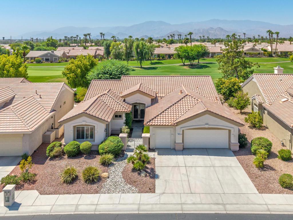 Sun City Palm Desert - Monaco Model. Perched above the 16th fairway, this sought-after Monaco estate home offers breathtaking panoramic views of the golf course and surrounding mountains. The south-facing backyard is perfect for entertaining, featuring a spacious patio, lush desert landscaping, built-in BBQ island, and a refreshing misting system. A gated front courtyard with leaded-glass French doors creates striking curb appeal. Inside, soaring 12-foot ceilings in the great room and foyer set a grand tone, with 10-foot ceilings throughout the rest of the home. Plantation shutters and extensive tile flooring add style and comfort. The great room boasts a double sliding door to the patio, while the family room offers a custom built-in media center. The chef's kitchen includes a large island with breakfast bar, slab granite counters, double wall ovens, smooth glass electric cooktop (gas line also in place), and raised-panel maple cabinetry--continued in the laundry and bathrooms. An expanded den off the great room can easily serve as a third bedroom or formal dining space. The primary suite features a bay slider to the patio, a large walk-in closet, dual sinks, soaking tub, and separate shower. The extended guest suite has French doors to the courtyard and a private bath with tub/shower. Additional highlights include an expanded laundry room with utility sink and abundant cabinetry, an oversized 2-car plus golf cart garage with storage space, recirculating hot water, and dual AC units (one new in 2022, the other in 2016).