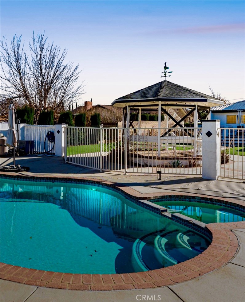 **Luxury Westside Pool and Spa Home with Outdoor Kitchen and Basketball Area** Welcome to this extraordinary Westside estate, perfectly situated in a highly desirable family-friendly neighborhood with excellent schools, and a true sense of community. On almost an acre of usable land, this home offers the ideal blend of comfort, luxury, and flexibility—perfect for large or multigenerational families.From the moment you arrive, the circular driveway and charming courtyard create stunning curb appeal, inviting you to experience the lifestyle that awaits. Step into a beautifully upgraded interior, featuring rich flooring, a warm fireplace, a cozy window seat, and elegant lighting that flows effortlessly into the formal dining area.The heart of the home is the spacious kitchen, designed for both daily life and entertaining. It features gleaming quartz countertops, abundant cabinetry, a walk-in pantry, upgraded stainless steel appliances, and a sunny breakfast nook with direct access to the patio—an inviting space where meals and memories will be made.Downstairs offers a flexible living arrangement, complete with a Sun Room and an extra bedroom, along with a full bath—perfect for in-laws, or guests. Upstairs, you'll find three generously sized bedrooms and two more full bathrooms. The luxurious primary suite feels like a true retreat, offering a private balcony with sweeping views of your expansive backyard, along with a spa-like ensuite featuring a walk-in shower and tranquil ambiance.The backyard is where this home truly shines. Whether you’re hosting friends and family or simply unwinding after a long day, the custom-designed outdoor space has everything you need. A sparkling pool and relaxing spa anchor the yard, surrounded by multiple seating areas, a covered pergola, artificial turf, and lush landscaping. Along with an outdoor kitchen station for summer cookouts and a dedicated basketball area for endless fun.And the possibilities don’t stop there. With so much land, you have room to build your own detached ADU for rental income, extended family, or a private office. There's also plenty of space for a large workshop, RV parking, your toys and even animals—with a stylish custom chicken coop already on-site.Whether you're upsizing, planning for the future, or looking for a home that grows with you, this rare Westside gem offers more than just space—it offers opportunity.