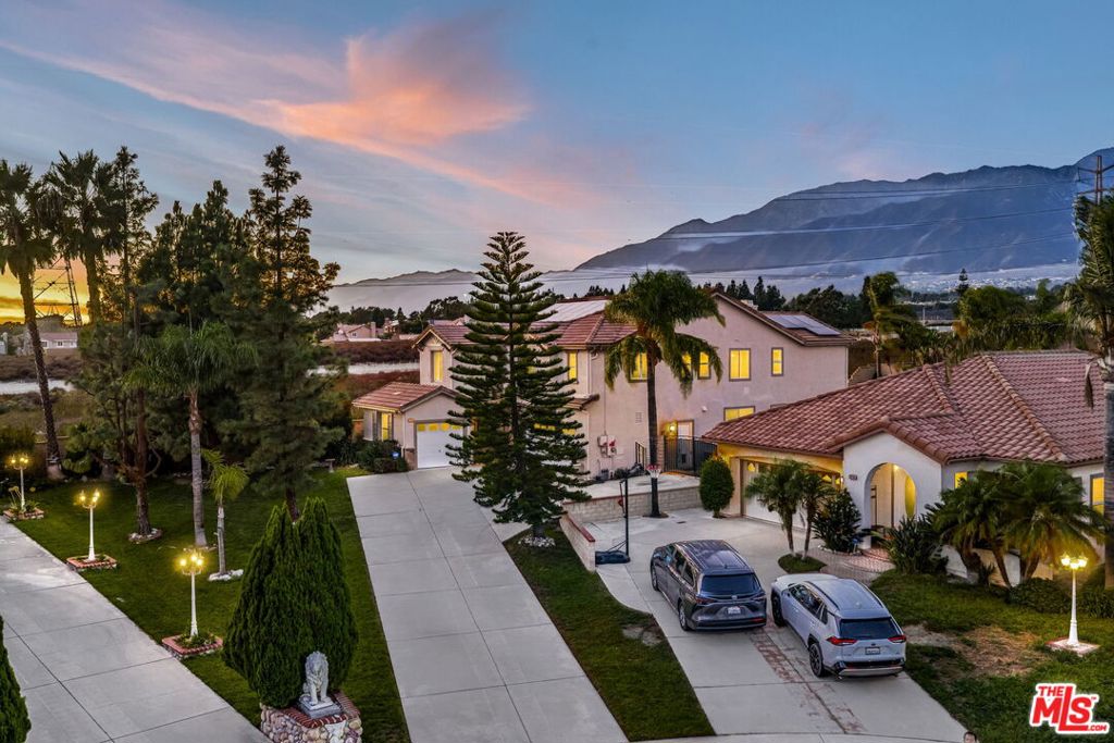 Nestled on a quiet cul-de-sac in one of Rancho Cucamonga's most coveted neighborhoods, this turnkey 5-bedroom home pairs everyday comfort with elevated style. Within the award-winning school district and surrounded by scenic trails and mountain views, the residence spans over 2,900 square feet of thoughtfully designed living space. The entry opens to an airy floor plan where formal living and dining rooms are framed by soaring two-story ceilings, creating a grand yet inviting atmosphere. The kitchen, bright and functional, connects seamlessly to the family room where a cozy fireplace anchors the space. A versatile main-floor bedroom or office and a full bath with shower add convenience and flexibility. Upstairs, the expansive primary suite is a retreat of its own, filled with natural light and sweeping views. It offers a generous walk-in closet and a spa-inspired en-suite bath with dual sinks, a soaking tub, and a separate shower. Three additional bedrooms, a full bathroom, and an upstairs laundry room provide comfort and ease for everyday living. The backyard is a private oasis designed for both relaxation and entertaining. A fully upgraded in-ground pool and spa take center stage, complemented by an outdoor fireplace, multiple dining areas, and a large grassy yard, all set against the dramatic backdrop of the mountains. Additional features include solar panels, a three-car garage with ample overhead storage, an extended driveway with room for multiple vehicles, and a wide paved side yard ideal for RV or boat parking. Just minutes from top-rated schools, shopping, dining, and major freeways, this home offers the best of both convenience and lifestyle in a truly sought-after community.