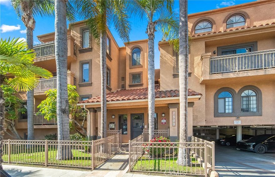 Welcome to this Mediterranean-style condominium located on a quiet cul-de-sac in the heart of Long Beach, less than two miles from the ocean. Unit #203 sits on the second floor of a friendly 24-unit community surrounded by manicured landscaping. Inside, step through the travertine foyer into a bright, open floor plan with vaulted ceilings. This 3-bedroom, 2-bath corner unit features custom laminate flooring, a sunny dining area, and a spacious living room that leads to a newly renovated balcony framed by palm tree views. The remodeled kitchen offers granite countertops, white cabinetry, and brand-new black and stainless-steel appliances are included. A tucked-away laundry room with washer and dryer and a nearby linen closet add convenience. The primary suite includes a walk-in closet and ensuite bath, while the two additional bedrooms feature mirrored wardrobes. The layout feels open and well-proportioned across roughly 1,000 square feet. Additional highlights include two tandem parking spaces in a secure, gated garage with 24-hour surveillance. With Long Beach’s continued coastal growth, this move-in-ready home is an excellent opportunity in today’s low-inventory market.