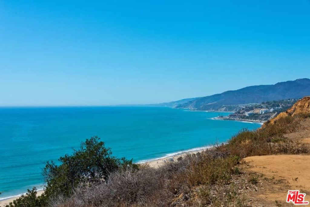 On a tranquil bluff overlooking the Pacific sits this exquisitely renovated 4 bed/ 5 bath mid-century jewel on 2 flat lots totaling 16,693 square-feet. Enjoy coastal living with panoramic ocean views and western sunsets while being just moments from the newly developed Palisades Village. The living/dining room opens in both directions with floor-to-ceiling glass - to the sea view in front and the covered patio and expansive yard in the back. The new, skylit kitchen is replete with center island, top-of-the-line appliances and generous banquette. Beyond is a guest suite (4th bedroom) with a study/sitting room and separate bedroom & bath. The bedroom wing consists of the primary suite with seaward views, sitting room and bath, plus two additional bedrooms all with en suite baths. Both wings encircle a covered terrace for outdoor dining and lounging. Surrounded by mature trees, the extensive gardens and decks have been landscaped by Jay Griffith, who created a secluded back sanctuary with spa for complete relaxation or entertaining. A unique living situation with further development or expansion possibilities.