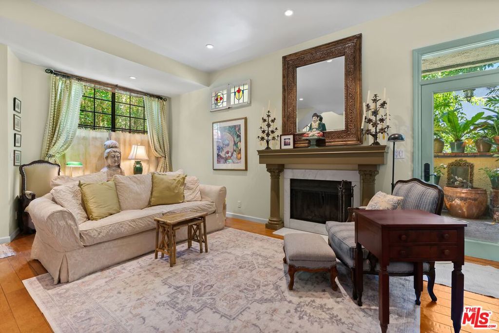 This charming tri-level townhouse feels more like a private home. An end unit in a smaller, well-maintained building, it offers exceptional privacy and a warm, inviting atmosphere. Hardwood floors run throughout (with tile in the bathrooms), and a fireplace adds cozy character to the spacious living room, which opens to a generous, custom-designed private patio made for the California indoor-outdoor lifestyle. The smartly designed galley kitchen flows easily into the main living areas, and green views grace every room. Upstairs, the spacious primary bedroom boasts soaring ceilings and an abundance of natural light. A truly lovely rooftop deck that you will use, with sweeping views of the Hollywood Hills. Additional features include central heat and air, in-unit laundry, two side-by-side parking spaces in a gated garage, security cameras for the building, and low HOA dues that include earthquake insurance. Located just moments from the best dining, shopping, and lifestyle amenities in the area, this one checks all the boxes.