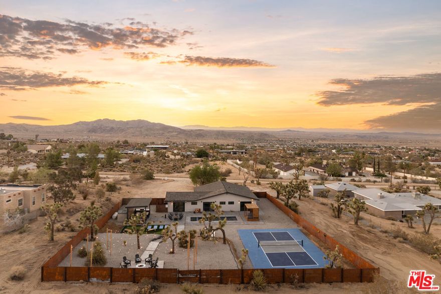 This beautifully remodeled modern retreat offers the ultimate blend of style, privacy, and income potential. Completed in 2022, the expansion and full renovation have transformed this property into a high-performing Airbnb, grossing over $175,000 annually. Ideally located in close proximity to Joshua Tree National Park, as well as local shops and dining, it offers guests and owners alike the perfect balance of convenience and seclusion.Set against a backdrop of breathtaking mountain views, the backyard is a true resort-style oasis featuring a sparkling swimming pool, relaxing spa, shaded cabana, communal fire pit, pickleball court, oversized chess set, and a putting green. Multiple lounge areas provide the perfect setting for both lively entertaining and quiet relaxation.Inside, the open-concept layout includes four bedrooms and three bathrooms, highlighted by a primary suite with an ensuite bath. The chef's kitchen boasts a large center island, premium appliances, and generous counter space, while the living room's electric fireplace sets a warm, inviting tone. Additional features include a covered patio, BBQ and alfresco dining area, central A/C, and full kitchen amenities. Whether as a lucrative short-term rental or a personal desert escape, this turnkey property delivers modern sophistication with resort-style living.